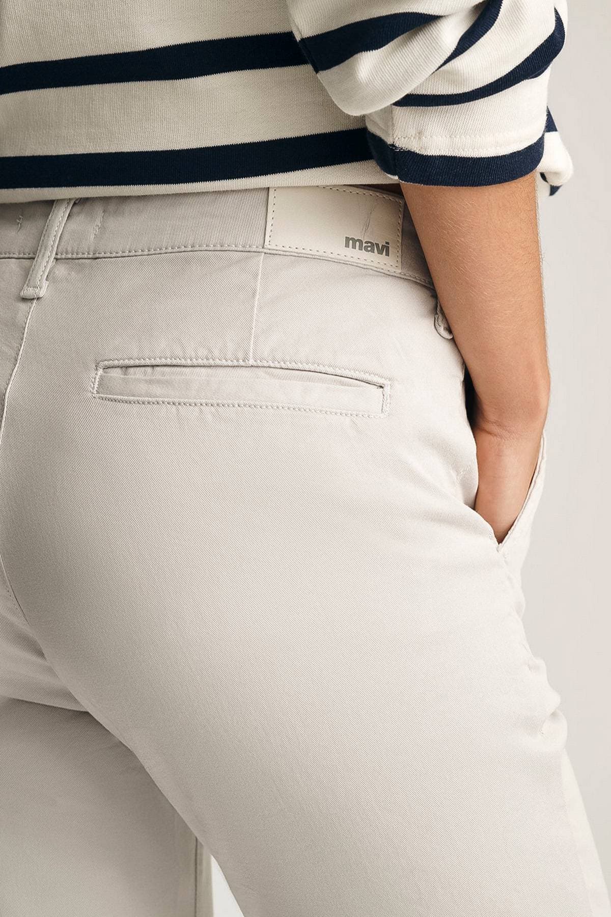 A person wearing light khaki pants with the brand name "mavi" visible on the waistband.