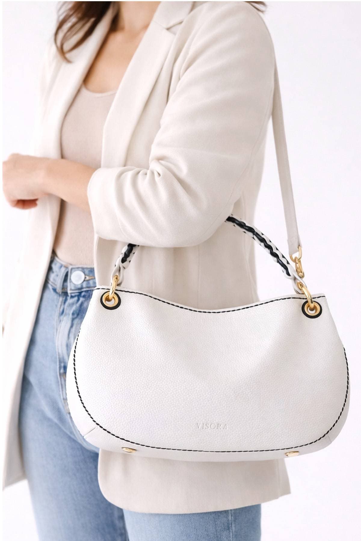 A woman holding a white leather handbag with gold hardware.