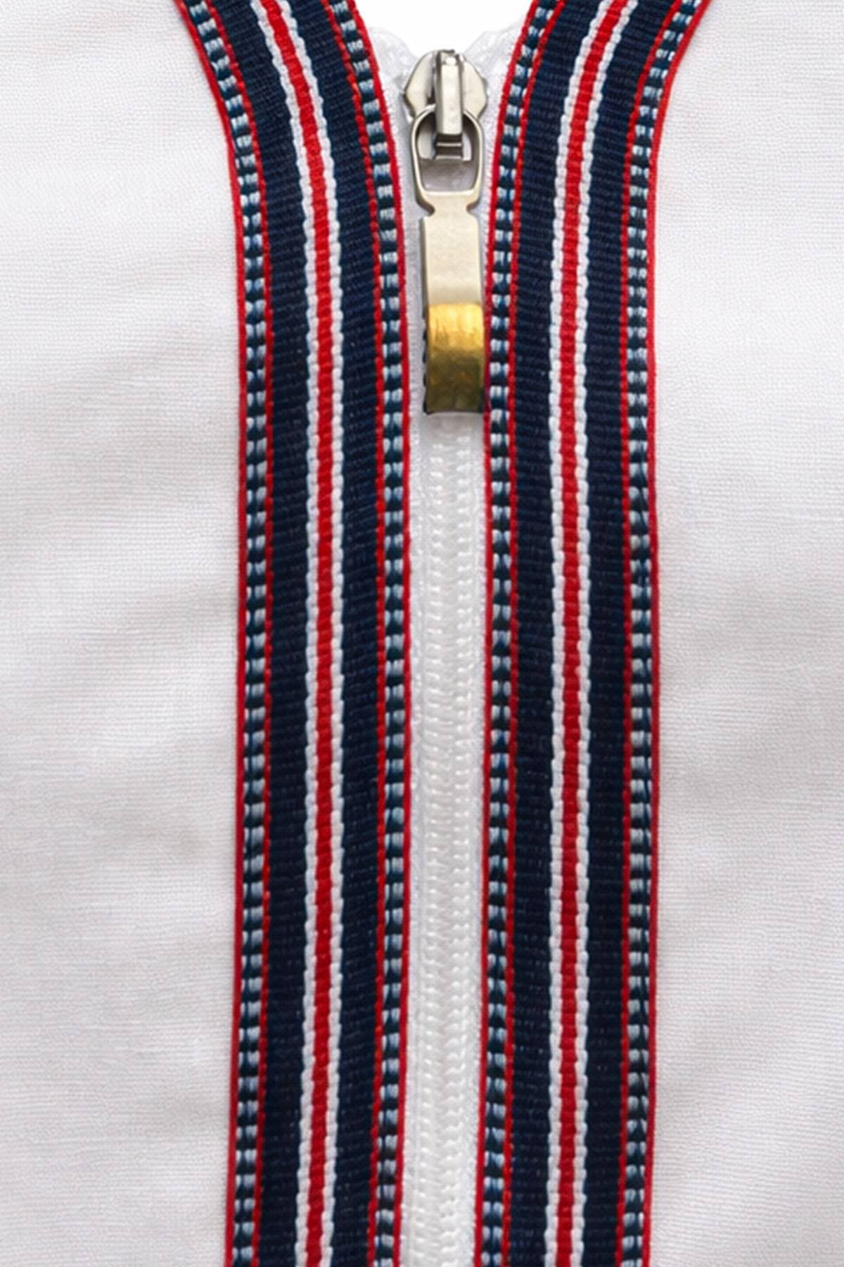 A close-up of a zipper with a pull tab on a garment featuring vertical stripes in red, white, and blue.