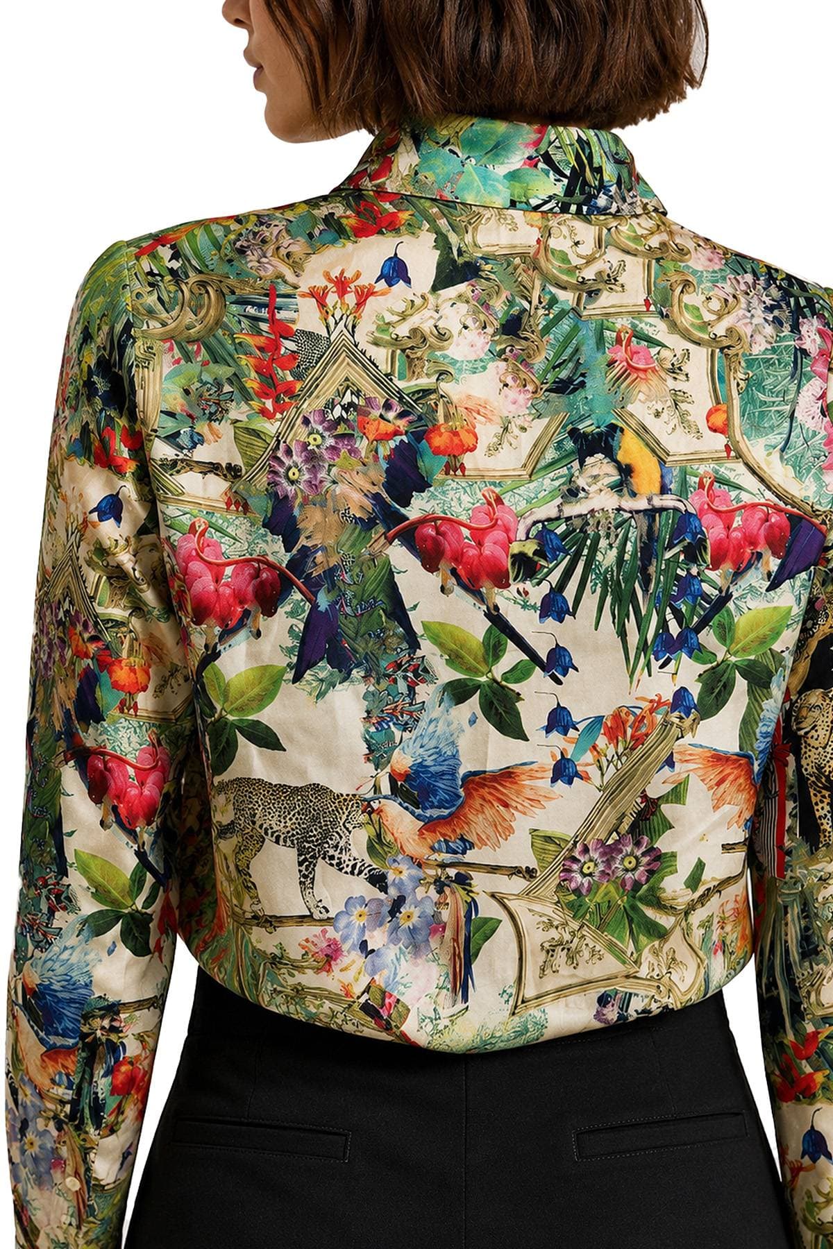 A person is wearing a vibrant, colorful shirt adorned with intricate floral and animal patterns.