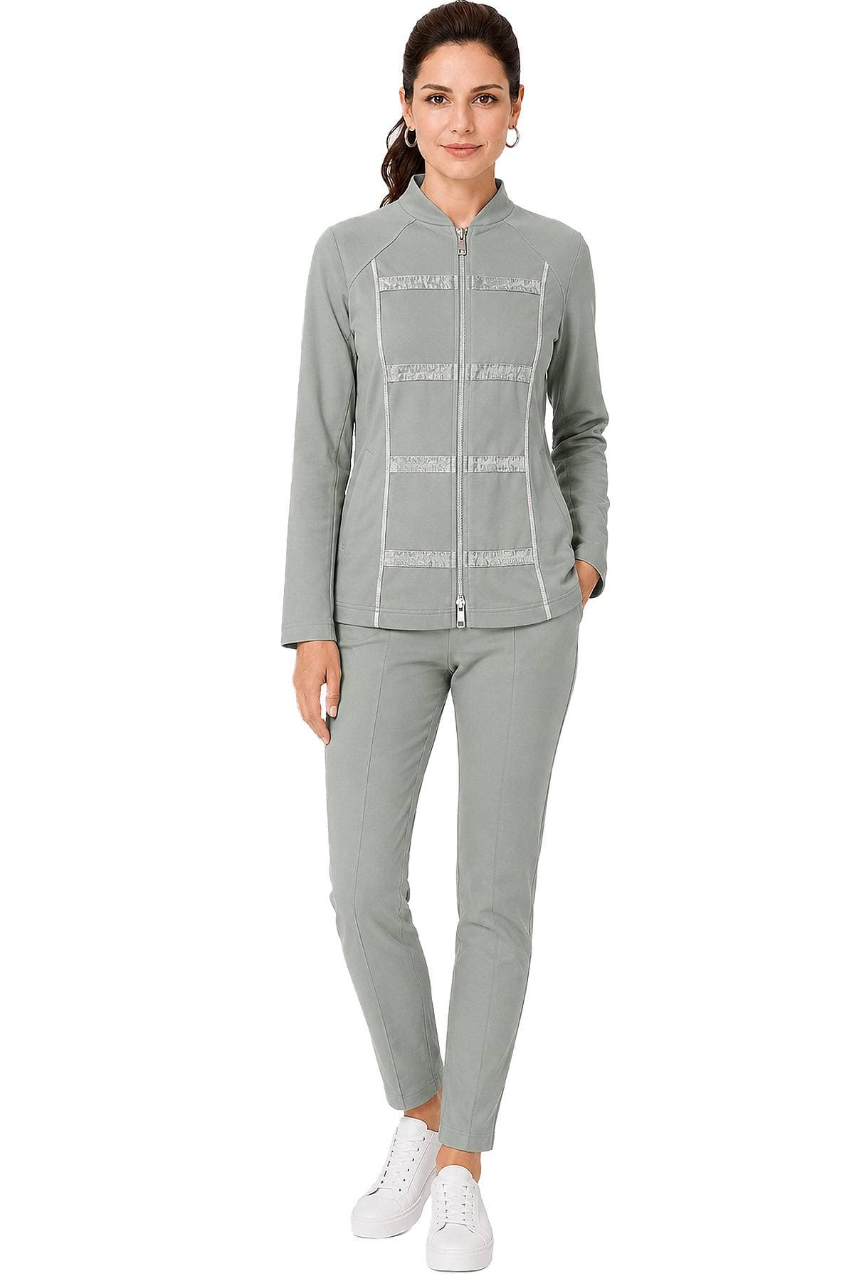 A woman wearing a light grey zip-up tracksuit with white sneakers.