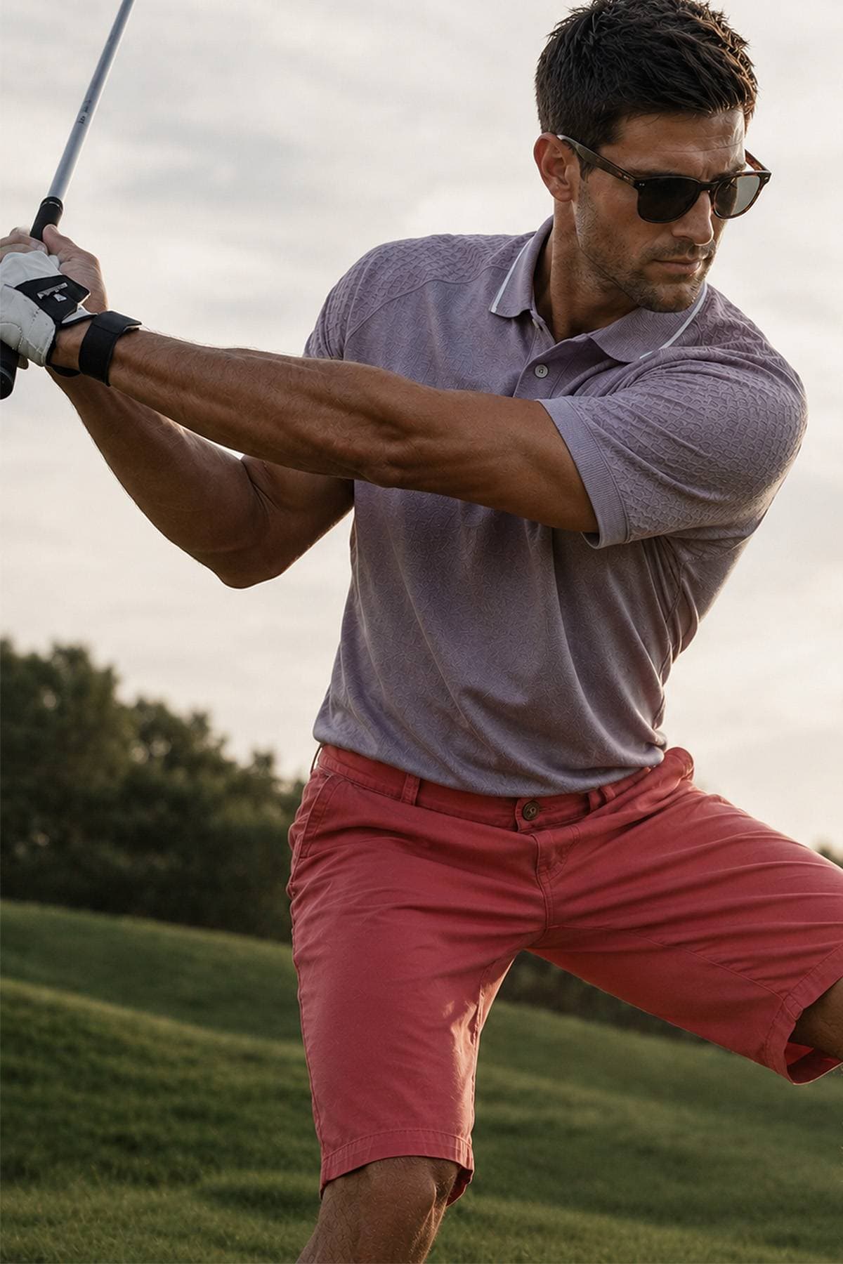 A man wearing sunglasses and a polo shirt is swinging a golf club.