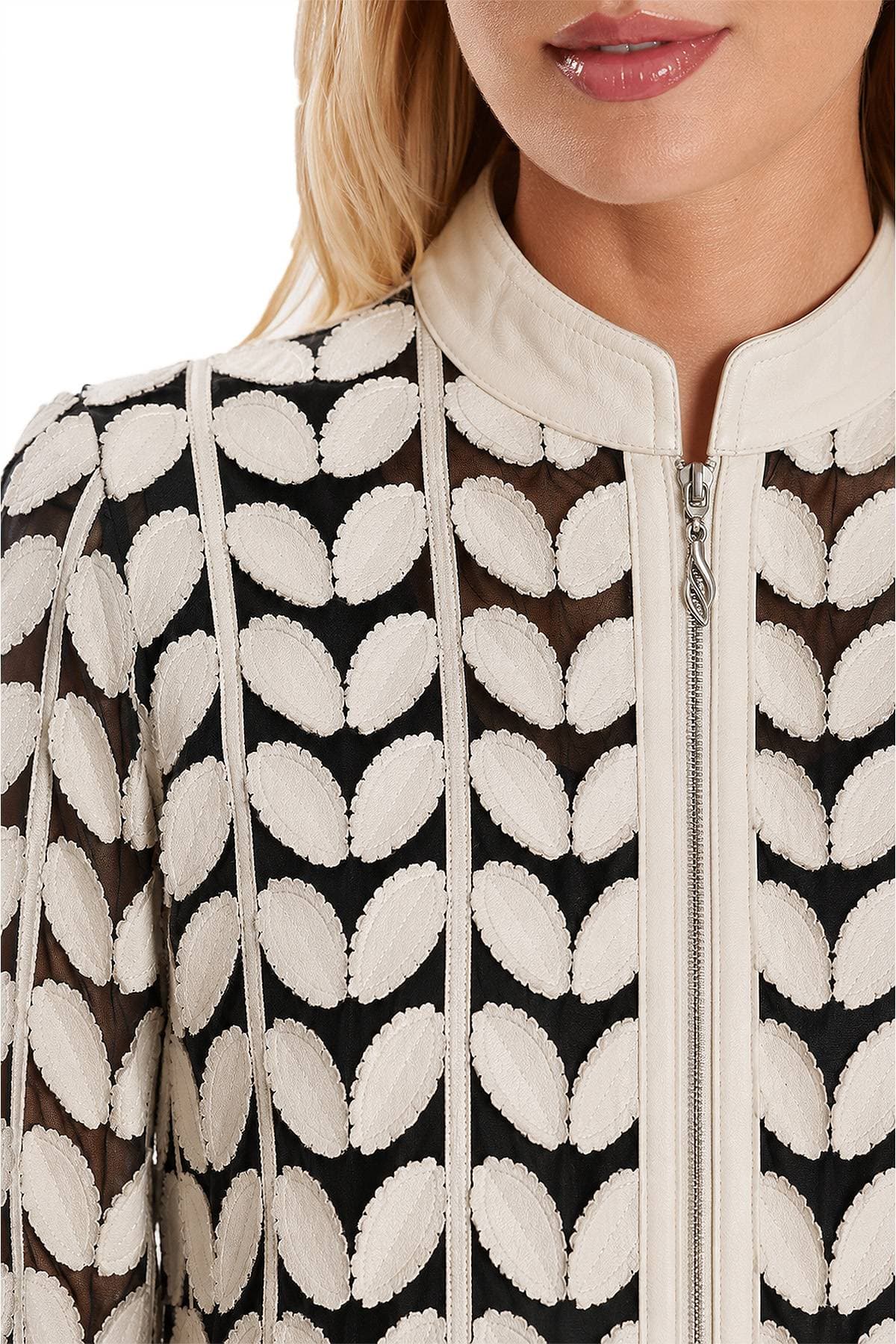 A person wearing a patterned jacket with white oval designs and a zipper.