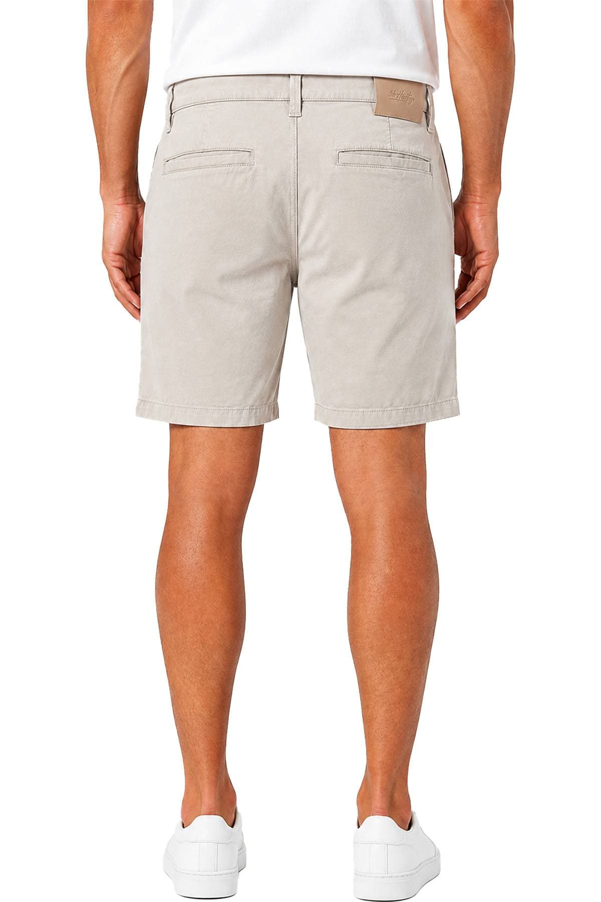 A person wearing beige shorts, a white shirt, and white sneakers is shown from the back.