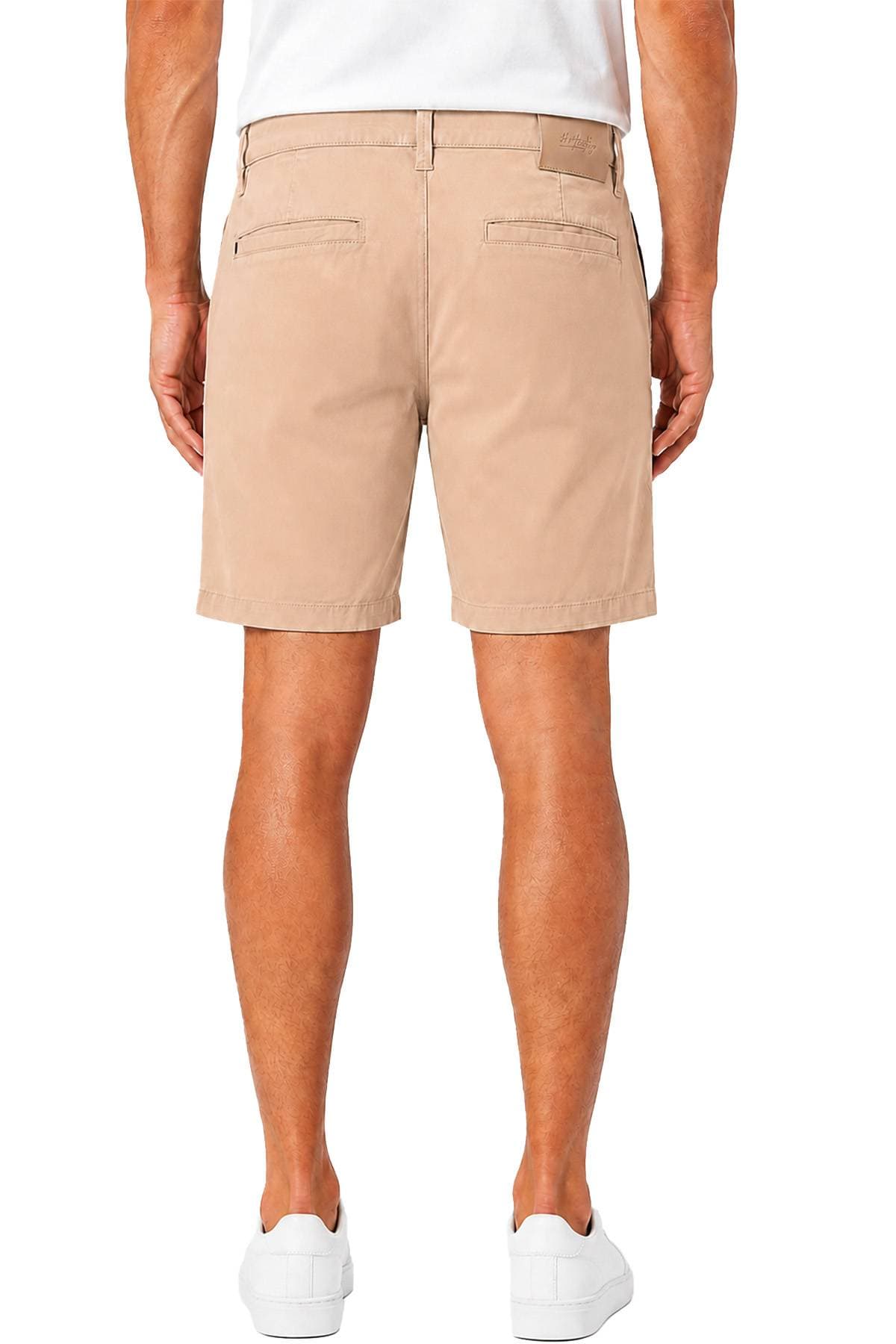 A person wearing beige shorts and white sneakers is standing with their back to the camera.