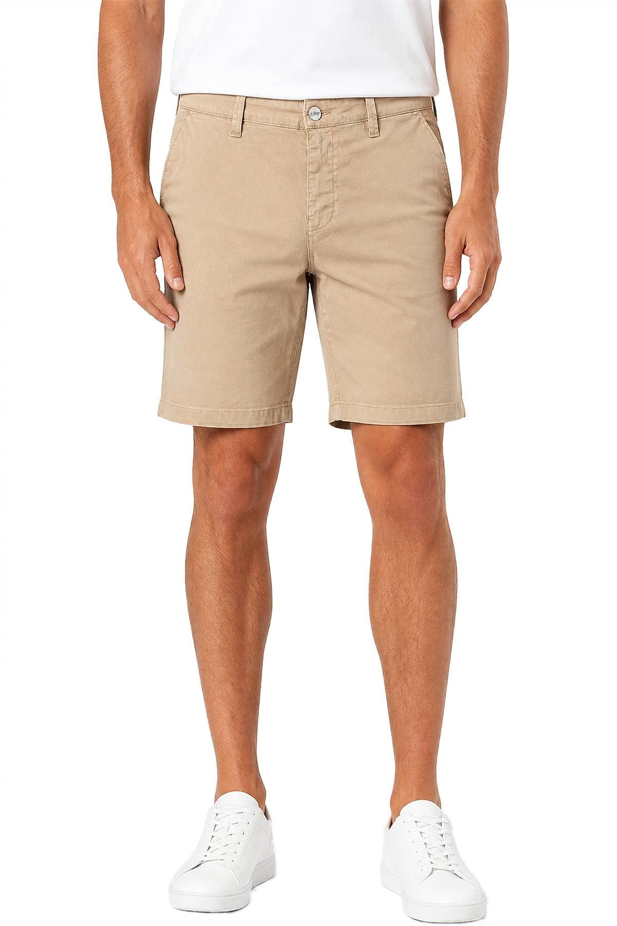 A person wearing beige shorts, a white shirt, and white sneakers stands facing forward.
