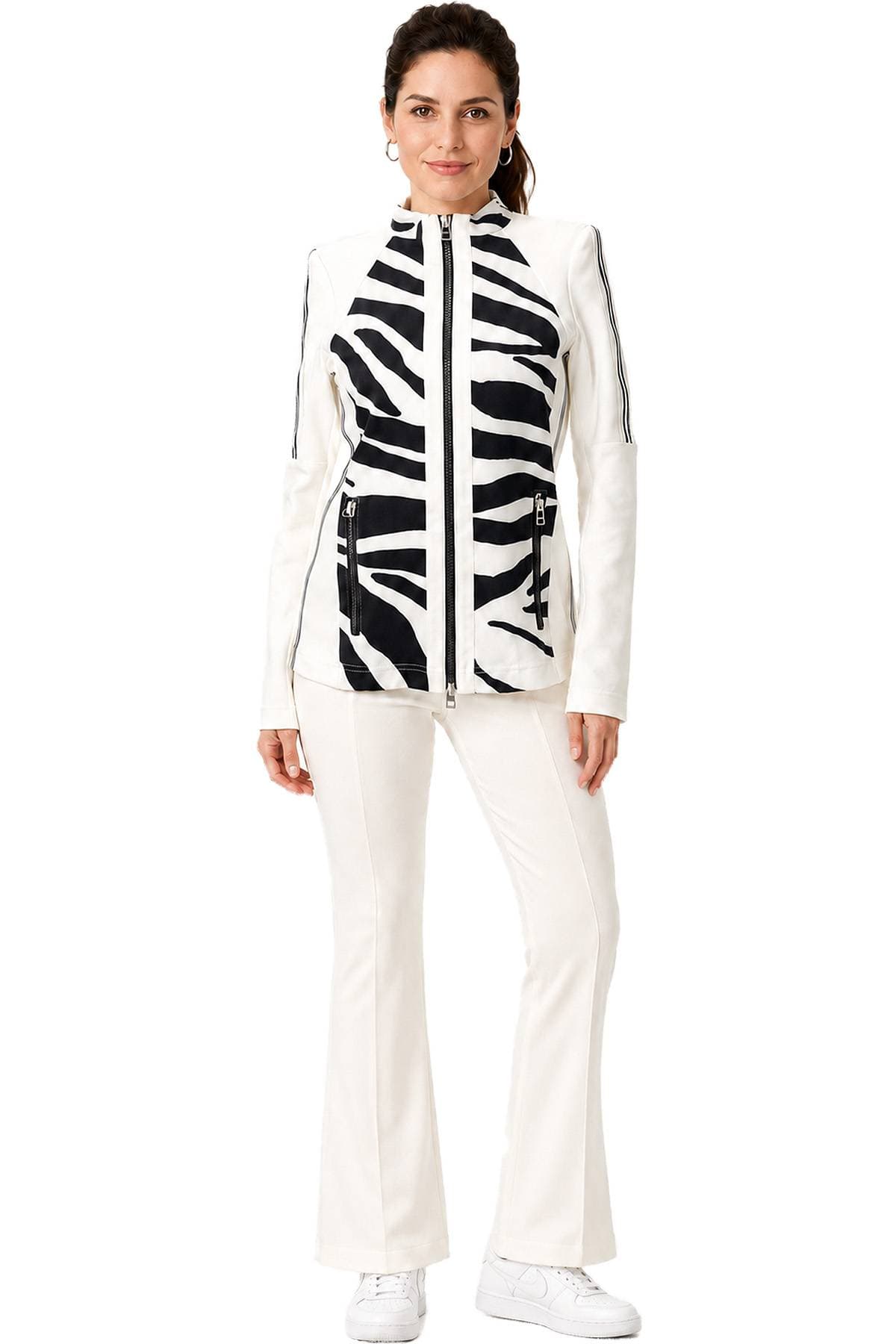 A person wearing a white and black zebra-patterned jacket with matching white pants and sneakers.