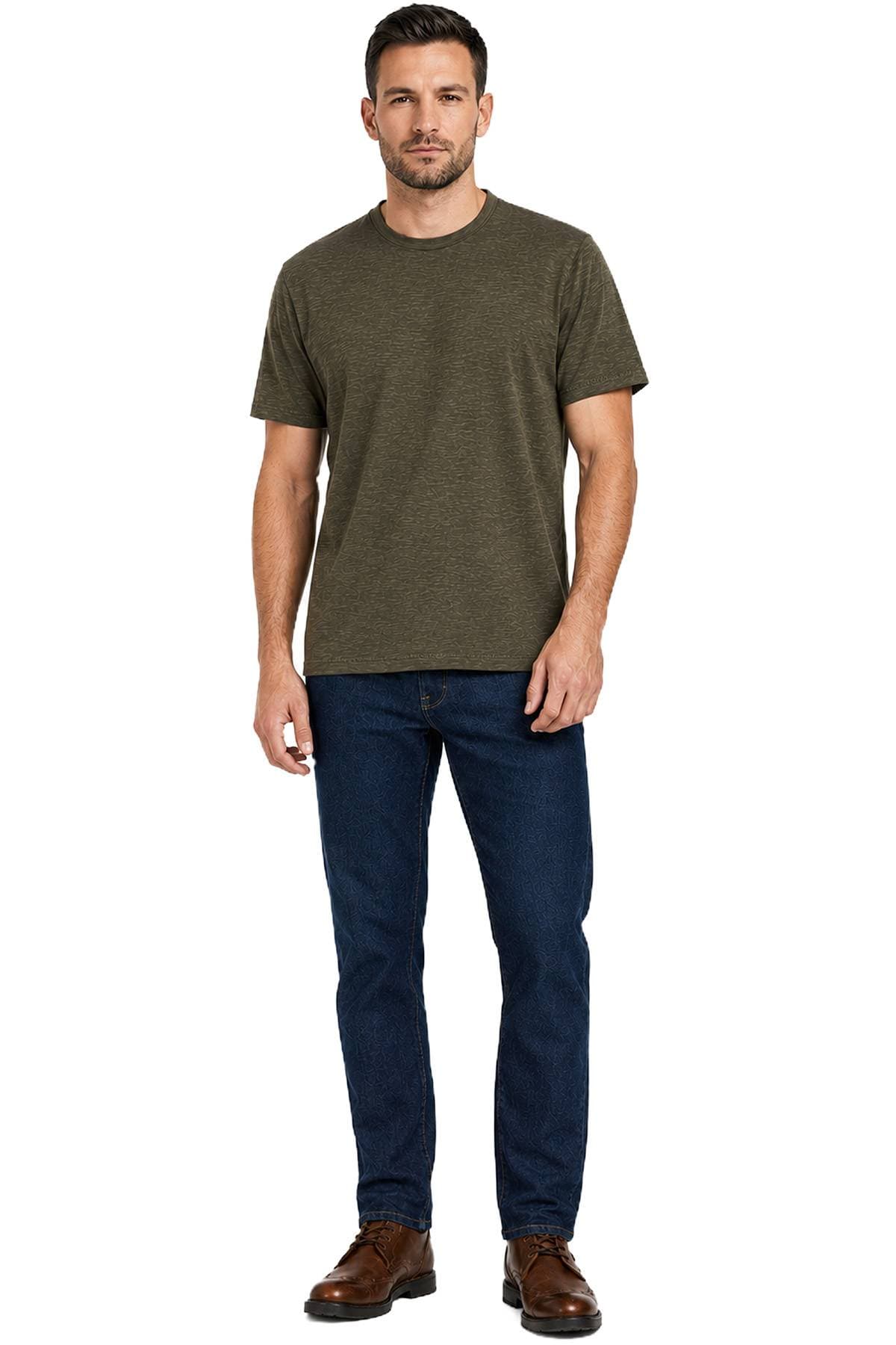 A man is wearing a dark green T-shirt, blue jeans, and brown shoes.