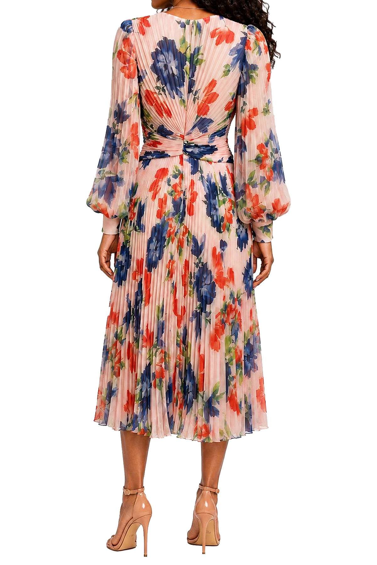 A person is wearing a colorful floral pleated dress with long sleeves and high-heeled sandals.