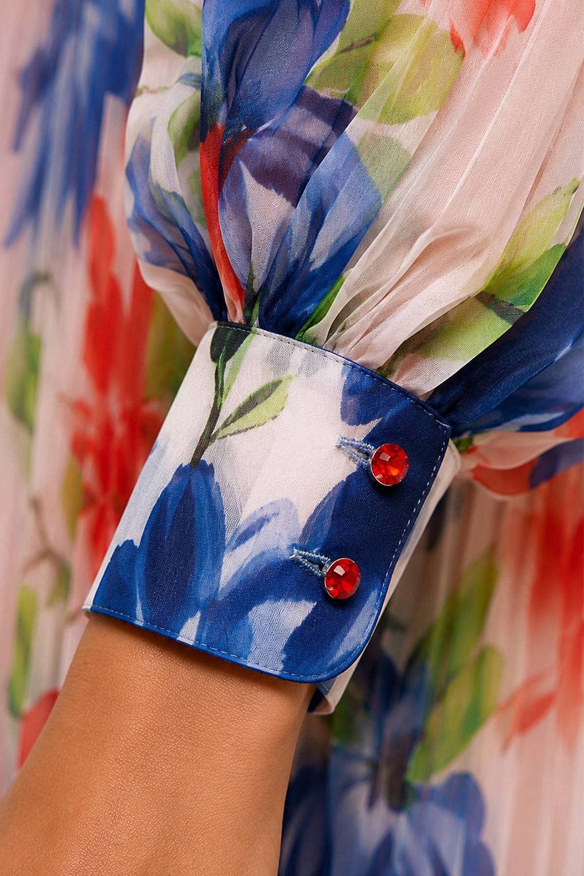 A sheer, colorful floral fabric cuff with two red buttons.