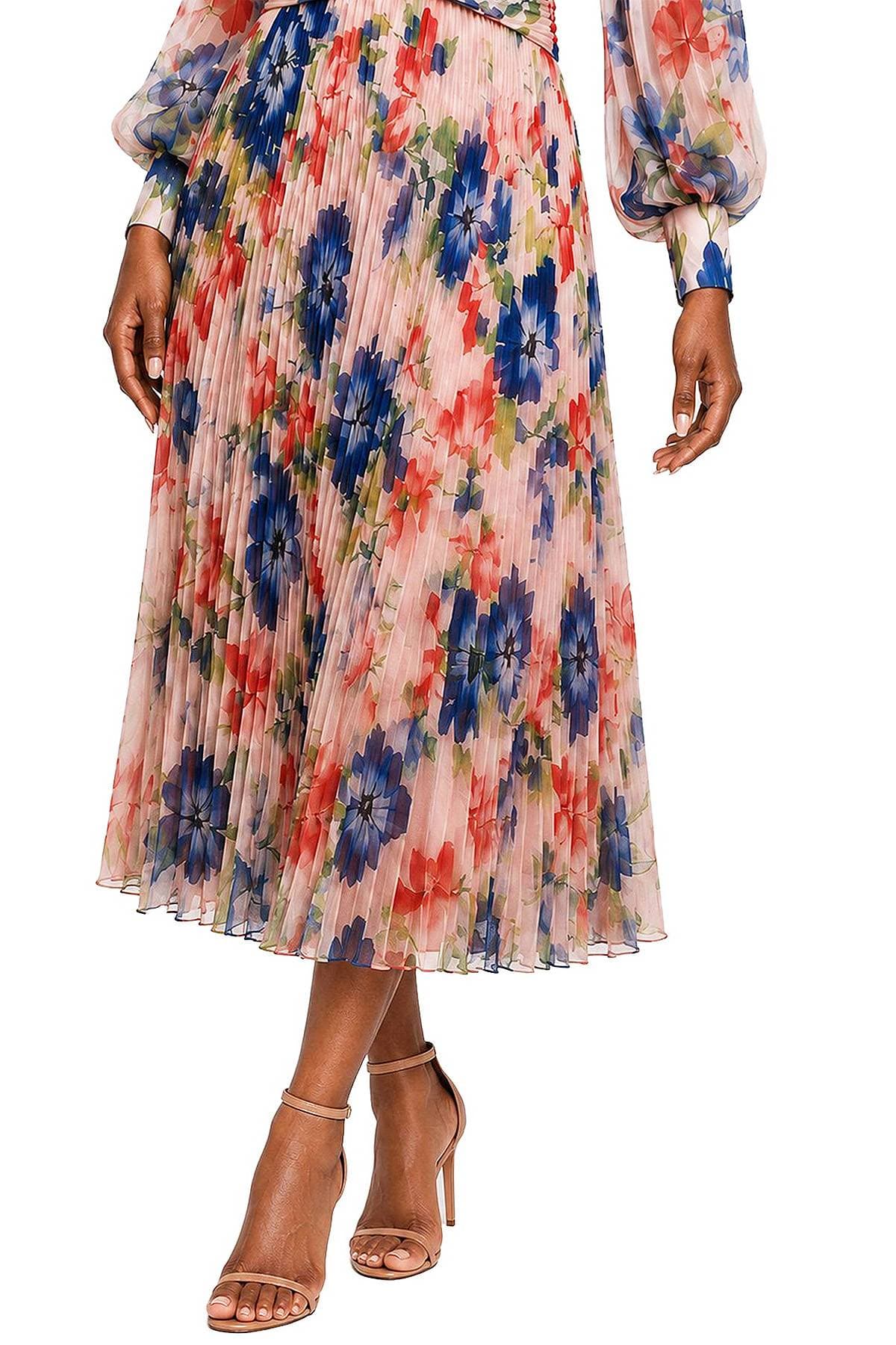 A person wearing a pleated floral skirt and heeled sandals.