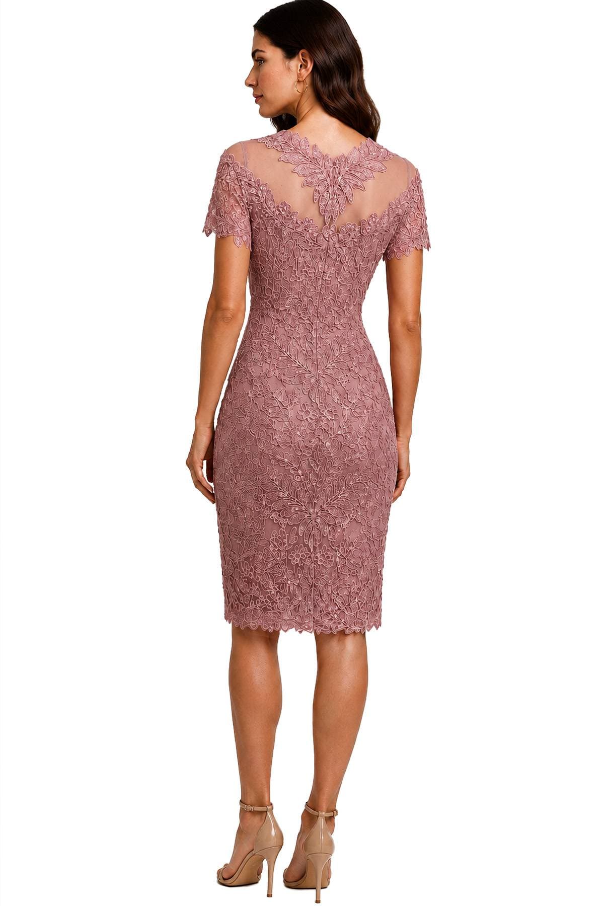 A woman is wearing a mauve lace dress with a sheer back and matching high heels.