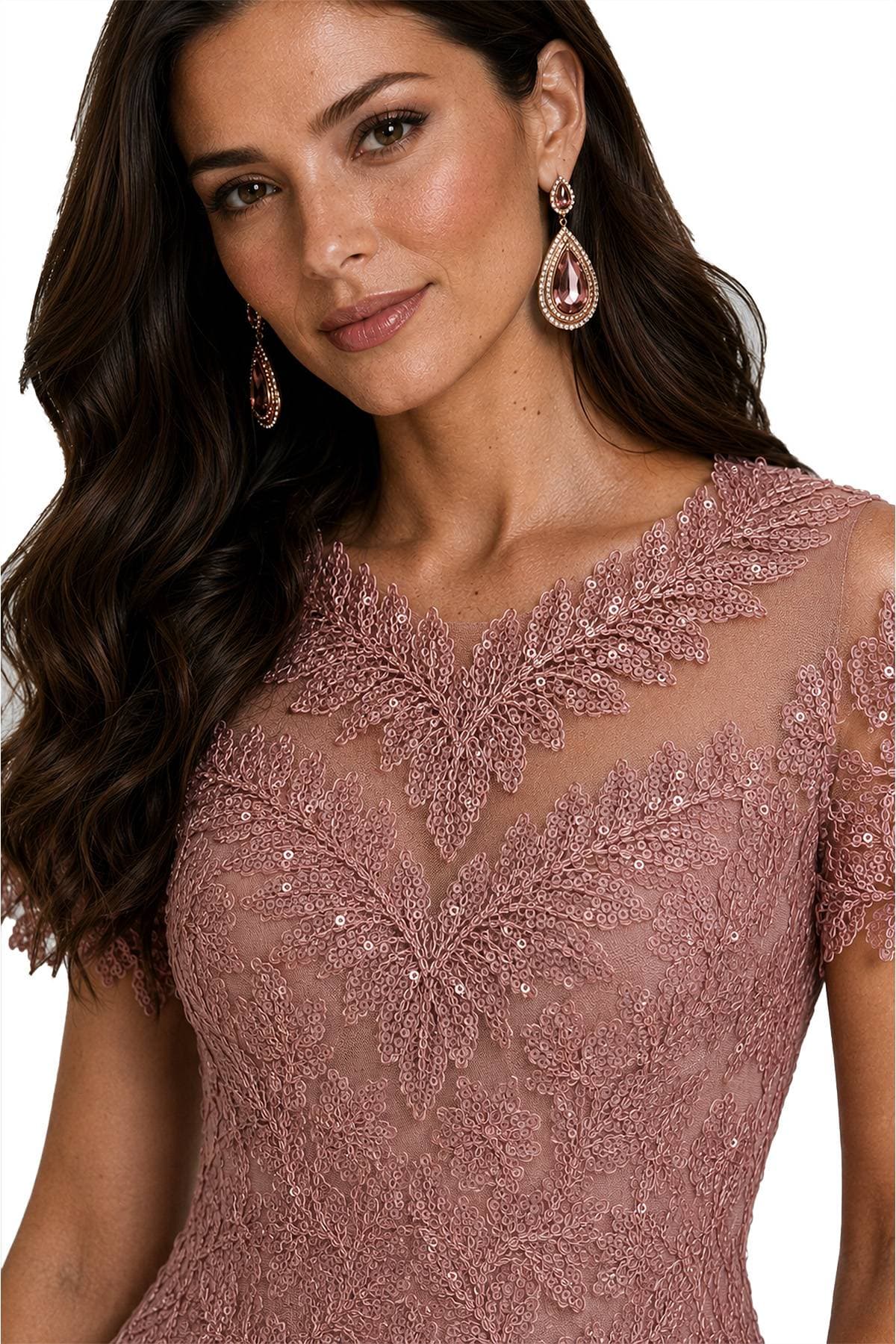 A woman is wearing a detailed pink lace dress with matching earrings.