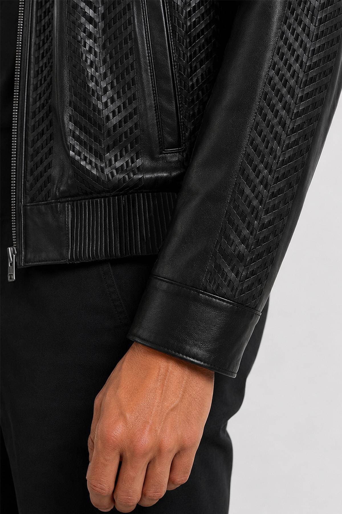 Close-up of a person wearing a black leather jacket with a textured pattern on the sleeves.