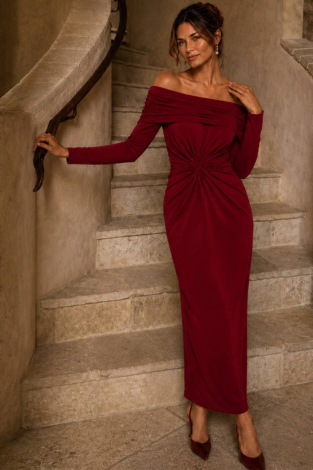 A woman in an off-shoulder, long-sleeved red dress poses on a staircase.