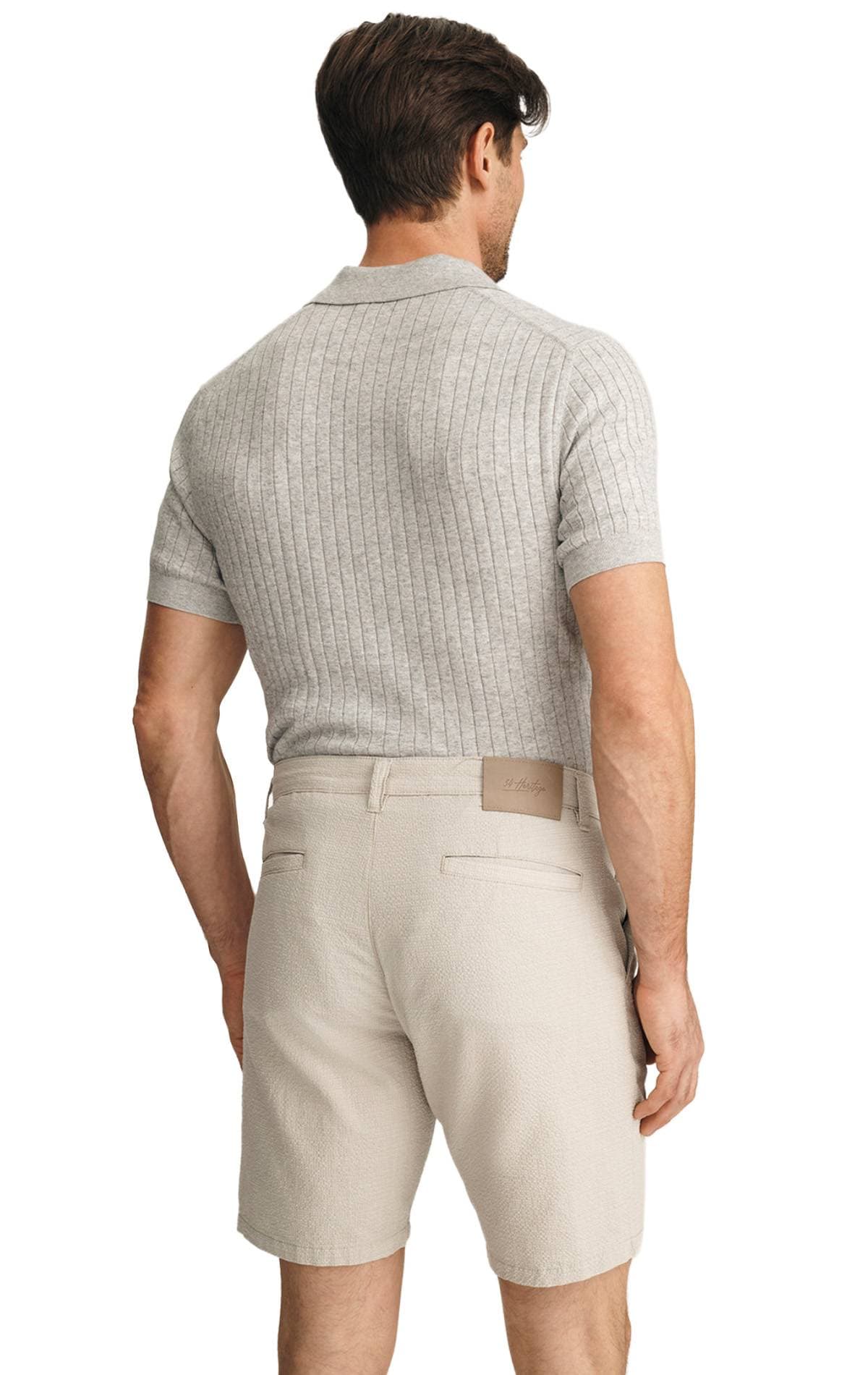 A man is wearing a gray ribbed short-sleeve shirt and beige shorts, seen from the back.