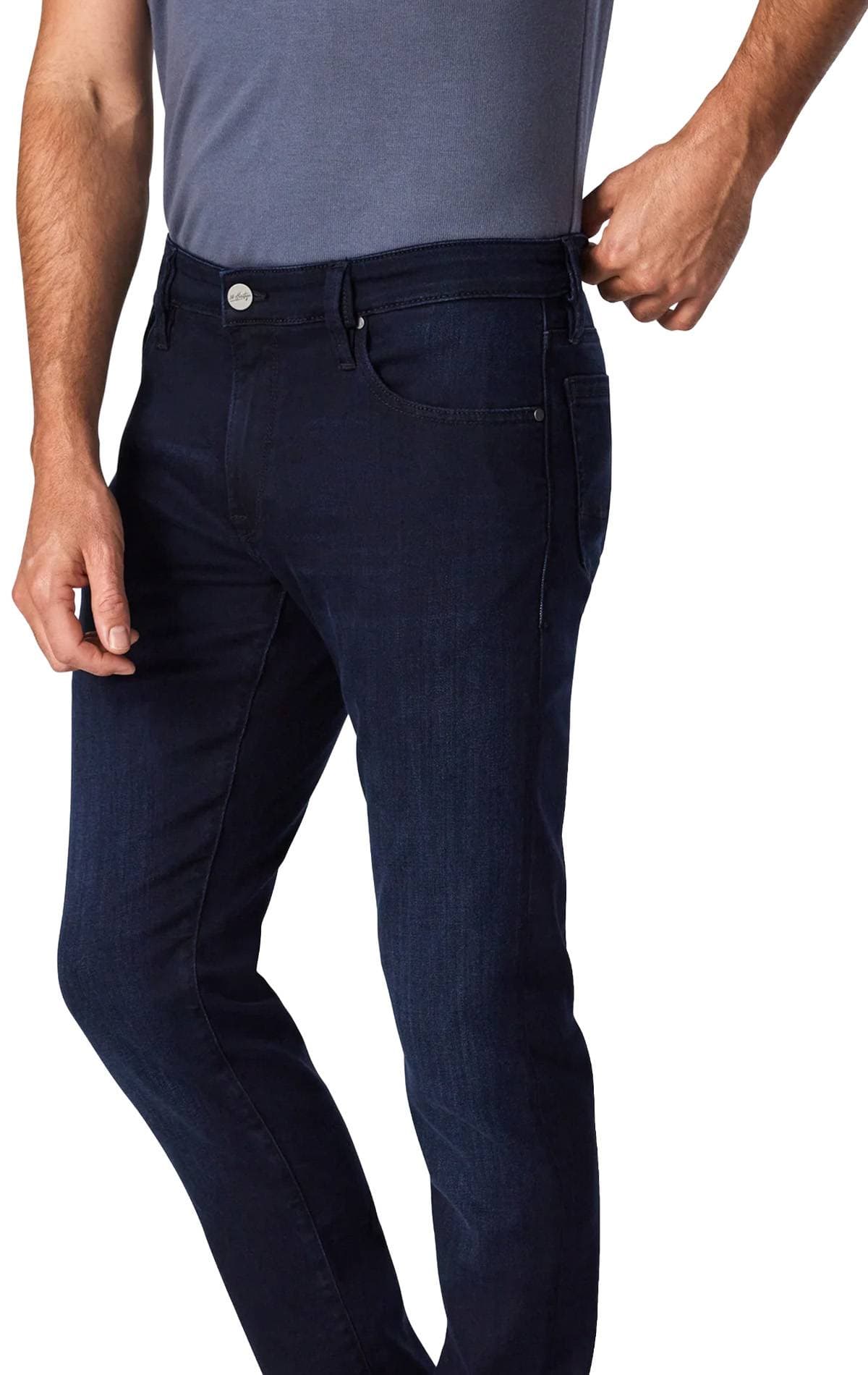 A person wearing dark blue jeans and a gray shirt, adjusting the waistband.