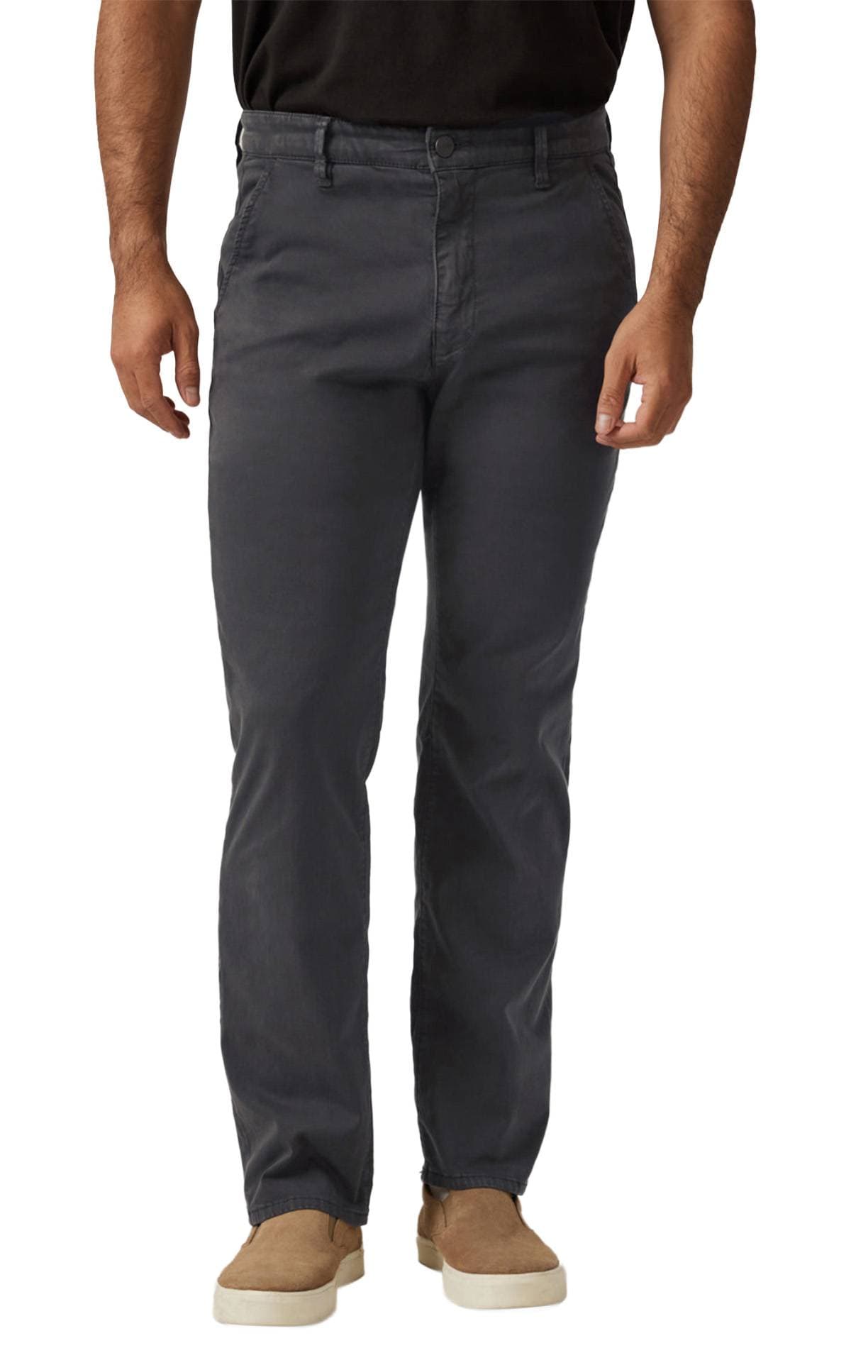 A person wearing dark grey pants and tan slip-on shoes.
