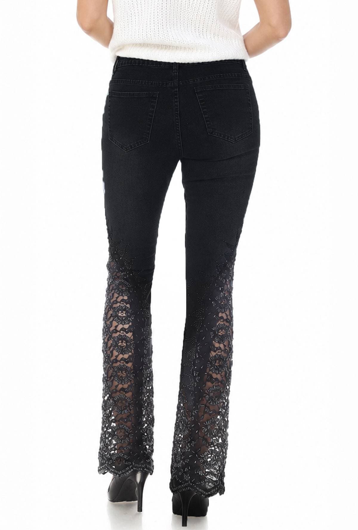 A person wearing black jeans with intricate lace detailing on the lower legs and high heels.