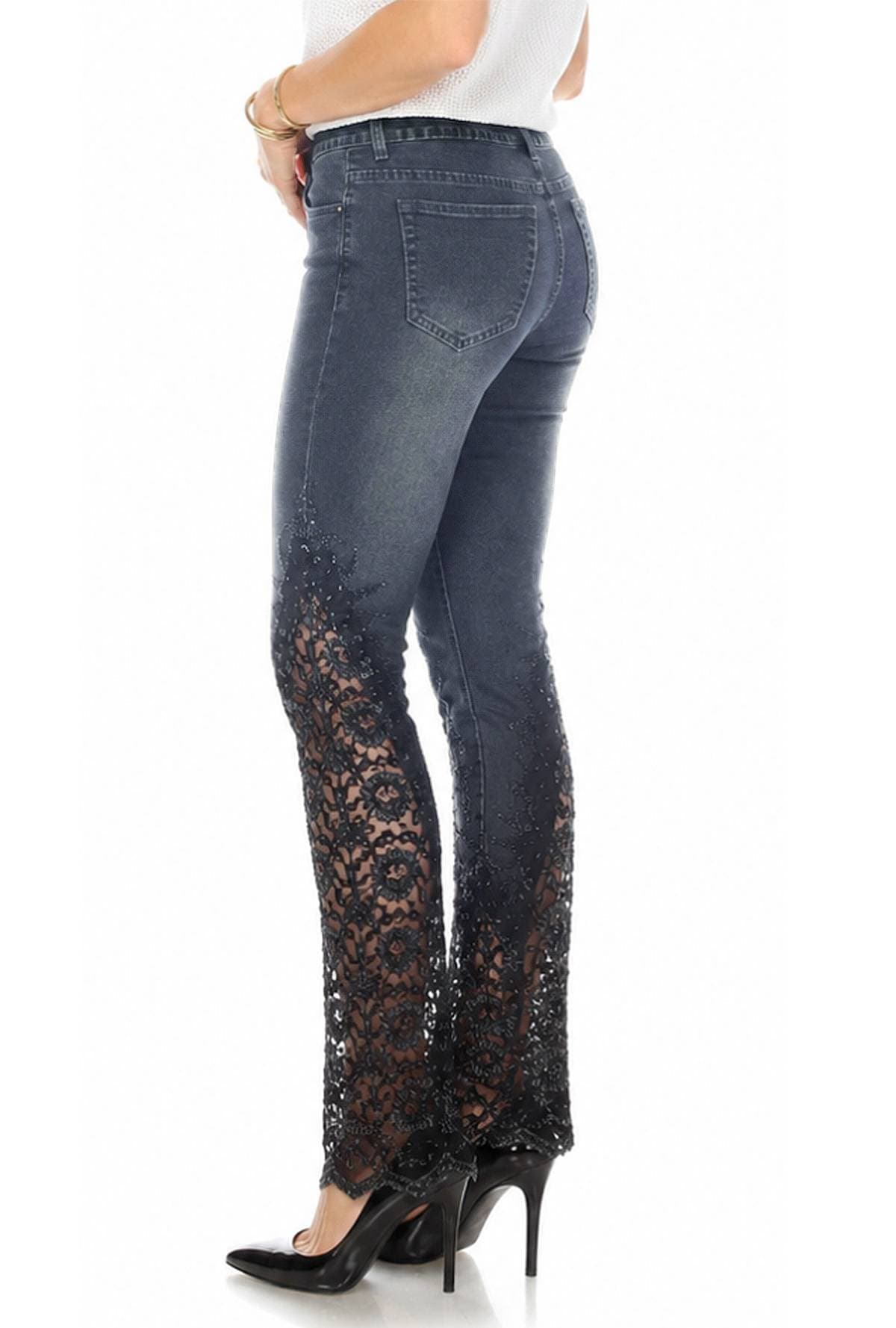 A person wearing dark jeans with intricate lace detailing on the lower legs and black high heels.