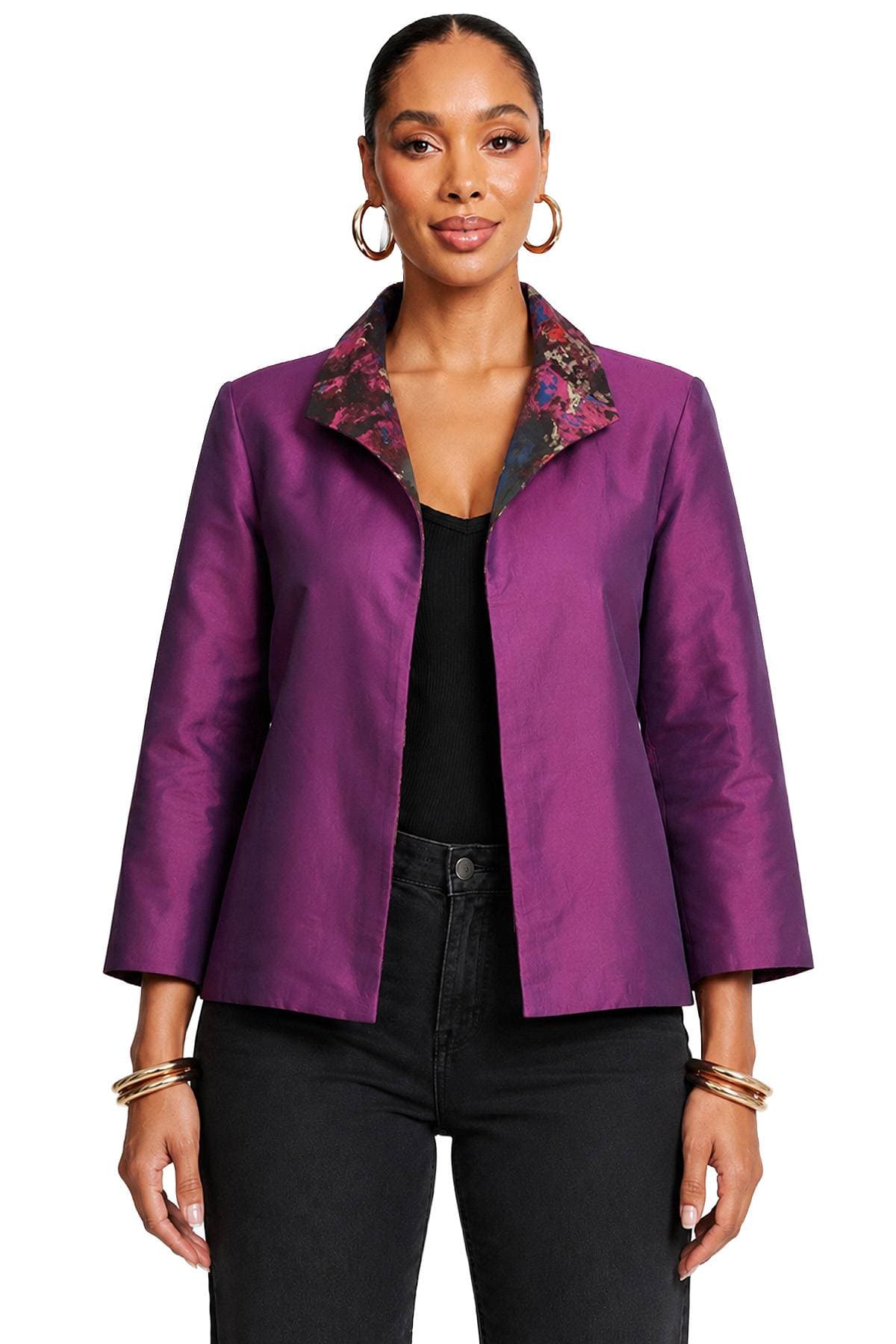 A woman wearing a purple jacket with a floral collar and hoop earrings.