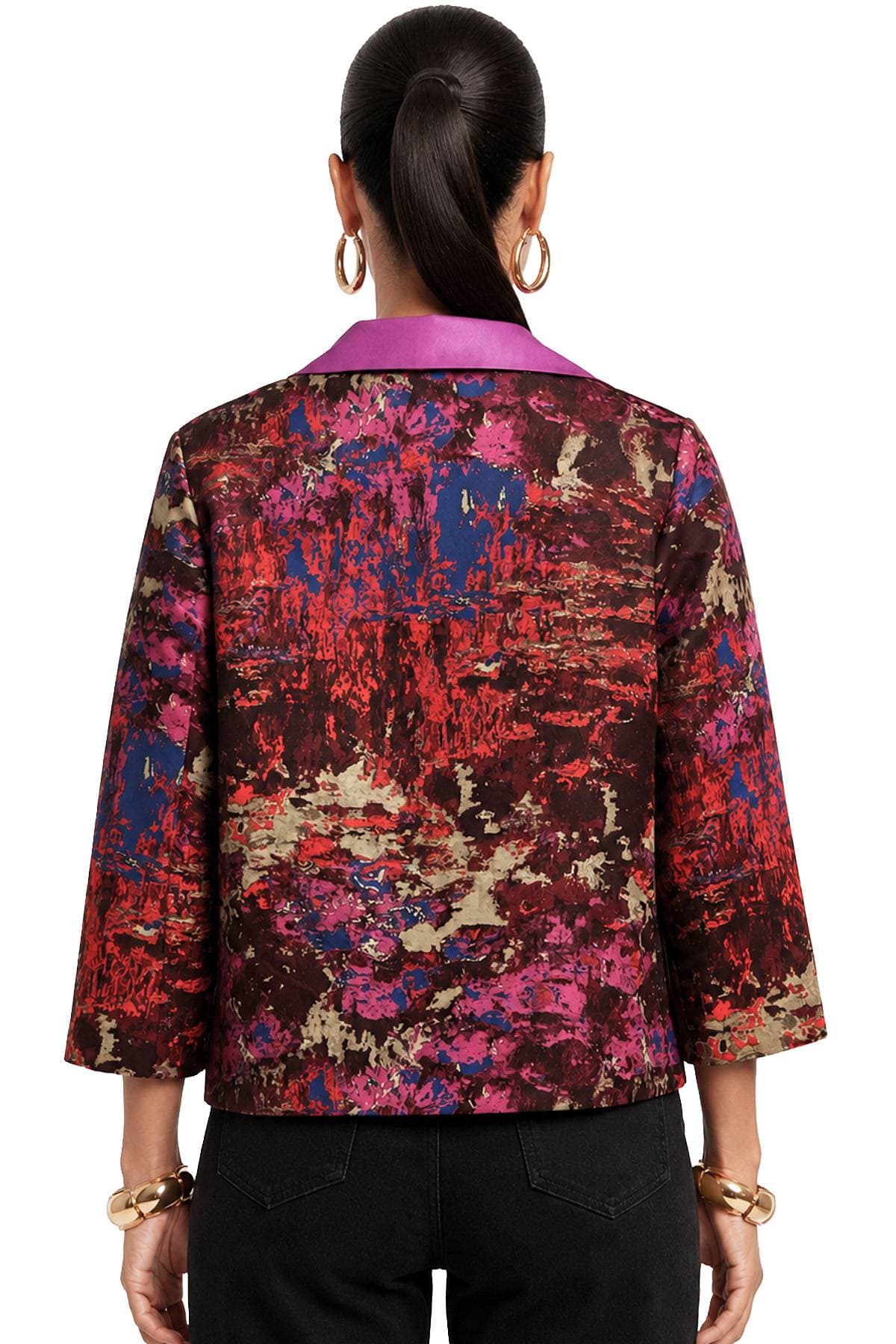 A person with a ponytail wears a brightly colored, abstract-patterned jacket.