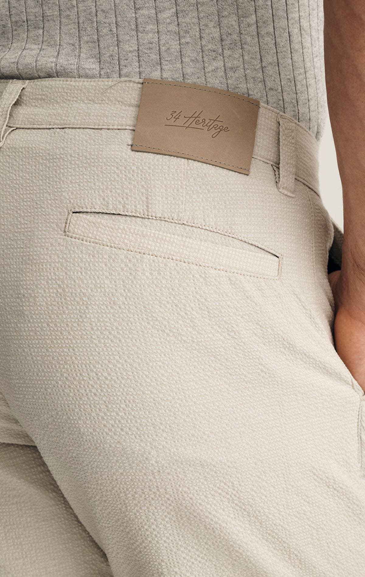 Close-up of beige textured pants with a "34 Heritage" label.