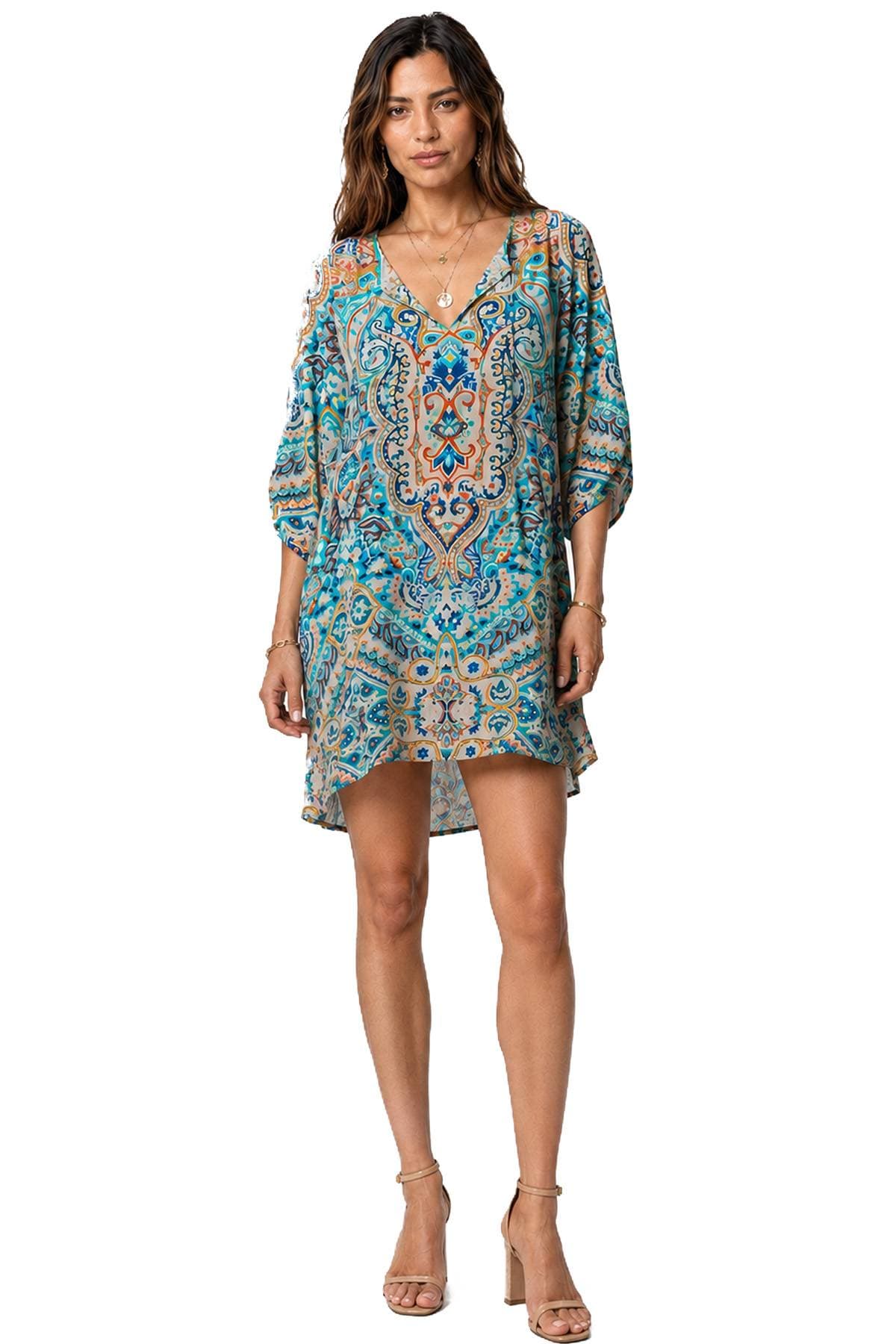 A woman is wearing a colorful, paisley-patterned dress and beige high-heeled sandals.