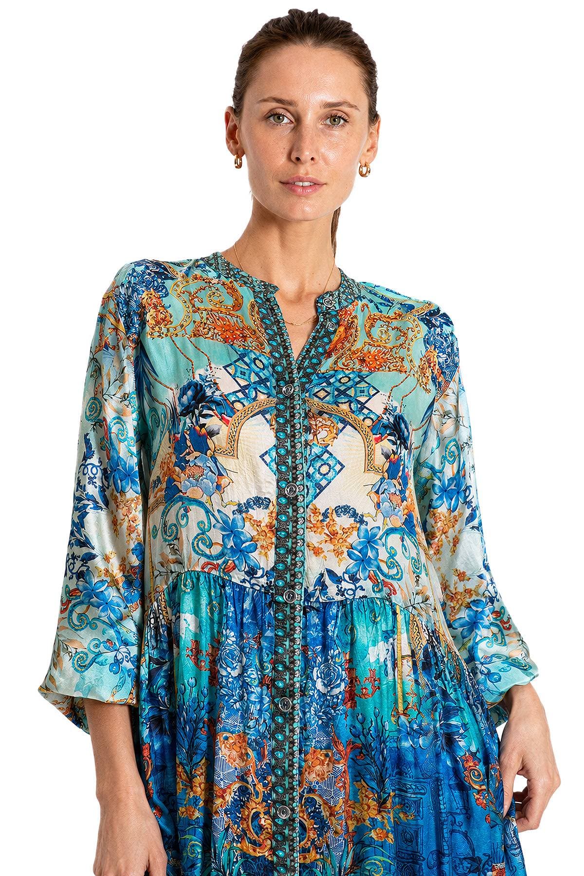 A woman wearing a colorful, intricately patterned dress with floral and geometric designs.