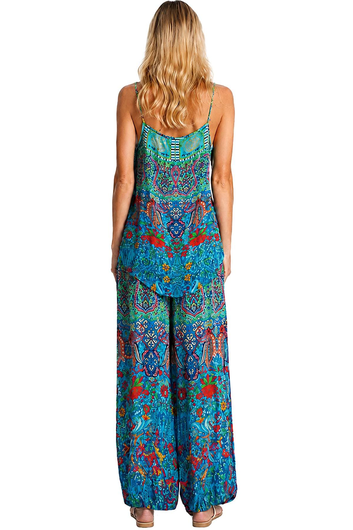 A person with long blonde hair is wearing a colorful, patterned jumpsuit with a flowing design.