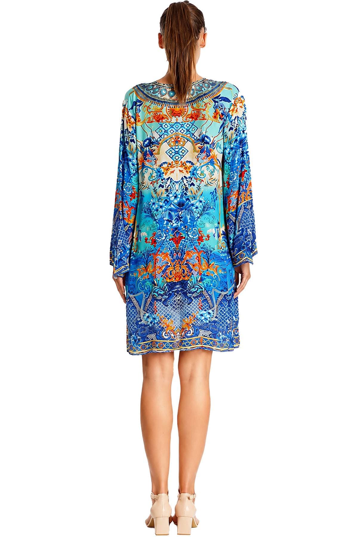 A woman wearing a colorful, patterned long-sleeve dress and beige high-heeled shoes is shown from the back.