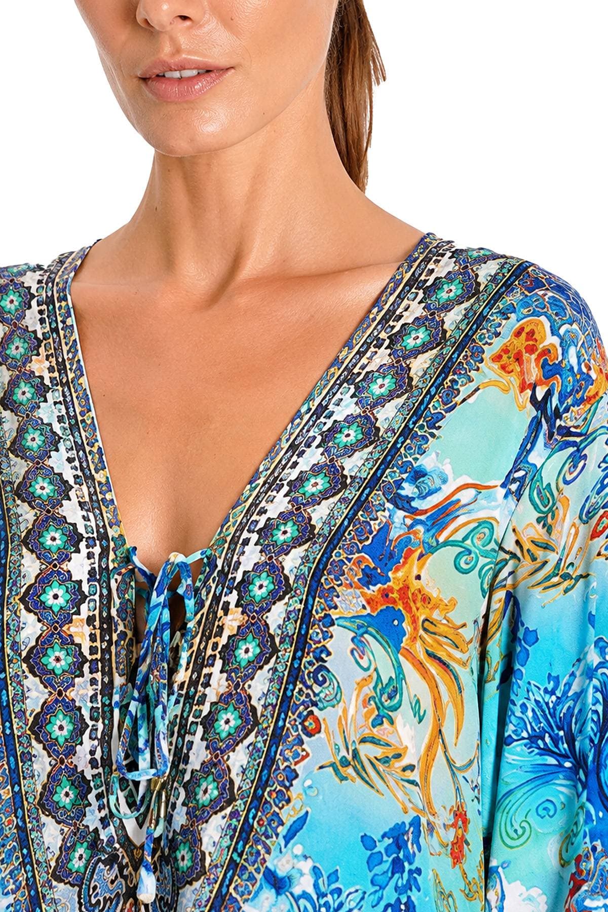 A person wearing a colorful, intricately patterned garment with a deep v-neck and drawstring.