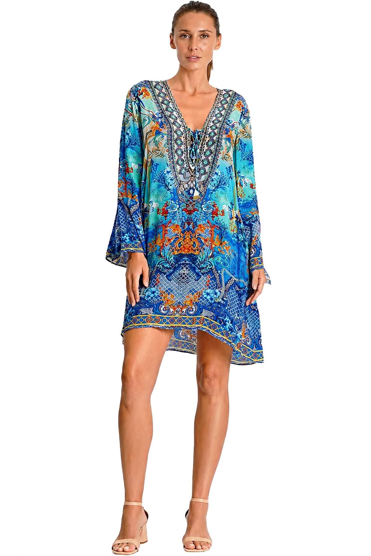 A person is wearing a blue and orange patterned dress with a deep V-neckline and beige heels.