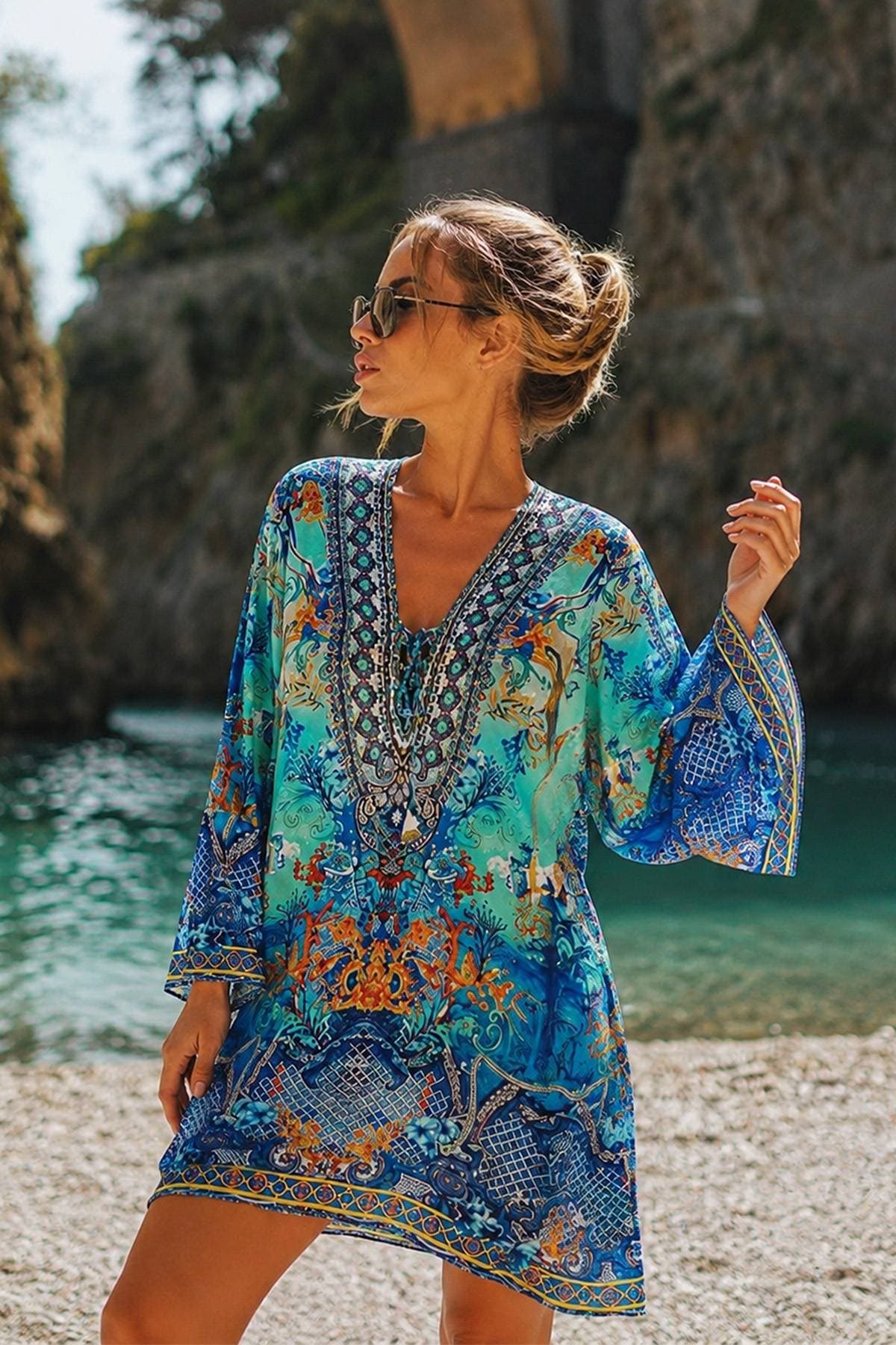 A woman in sunglasses is wearing a colorful, patterned dress.