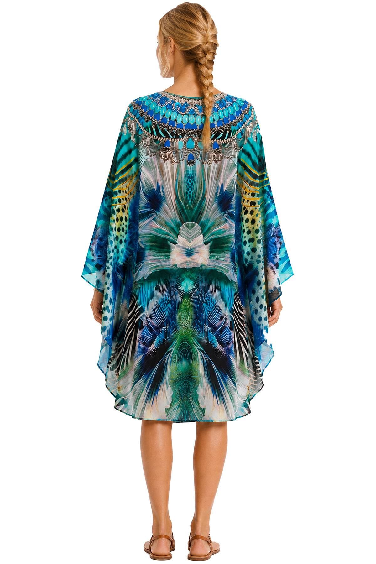 A person with braided hair wearing a vibrant, peacock-inspired kaftan.