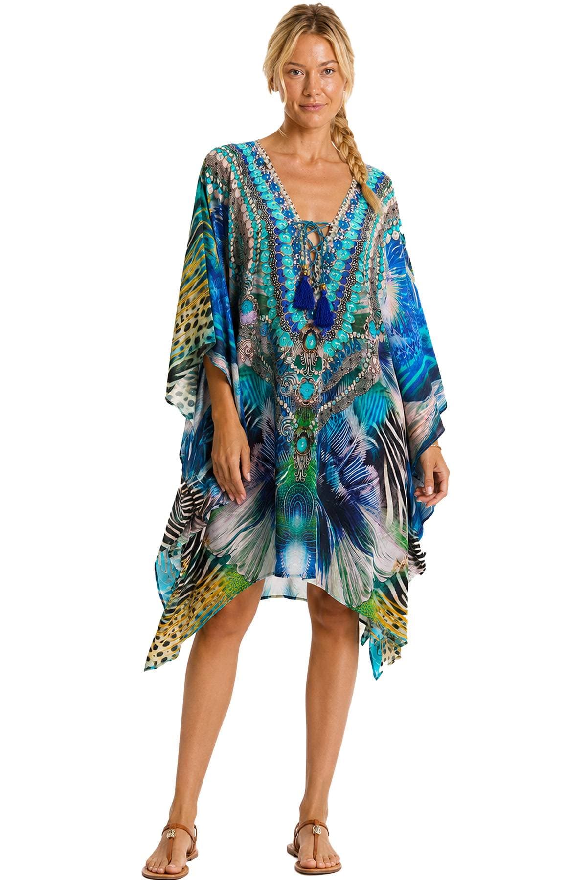 A woman is wearing a colorful, intricately patterned kaftan with blue tassels.