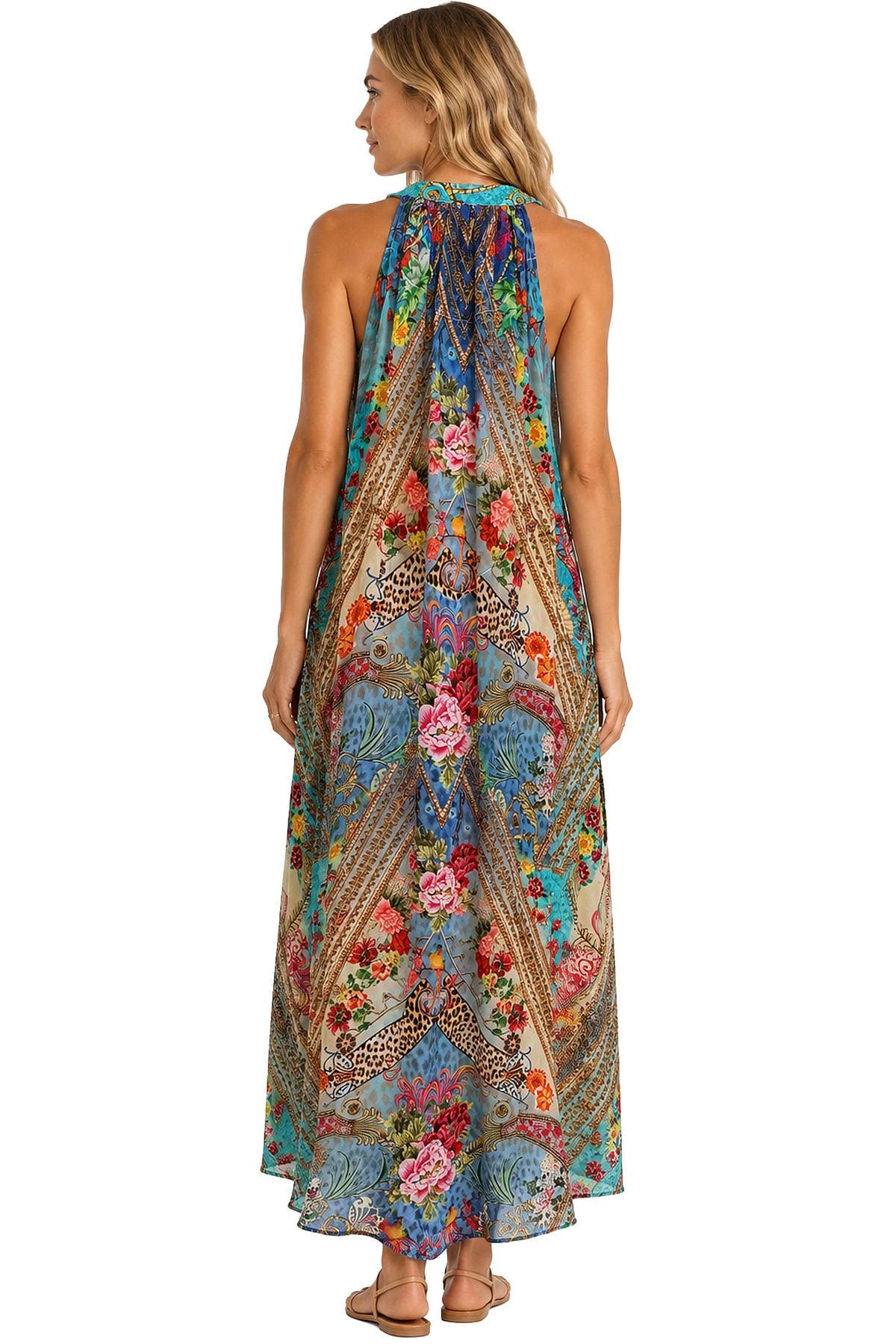 A woman is wearing a colorful, floral-patterned maxi dress with an intricate design.