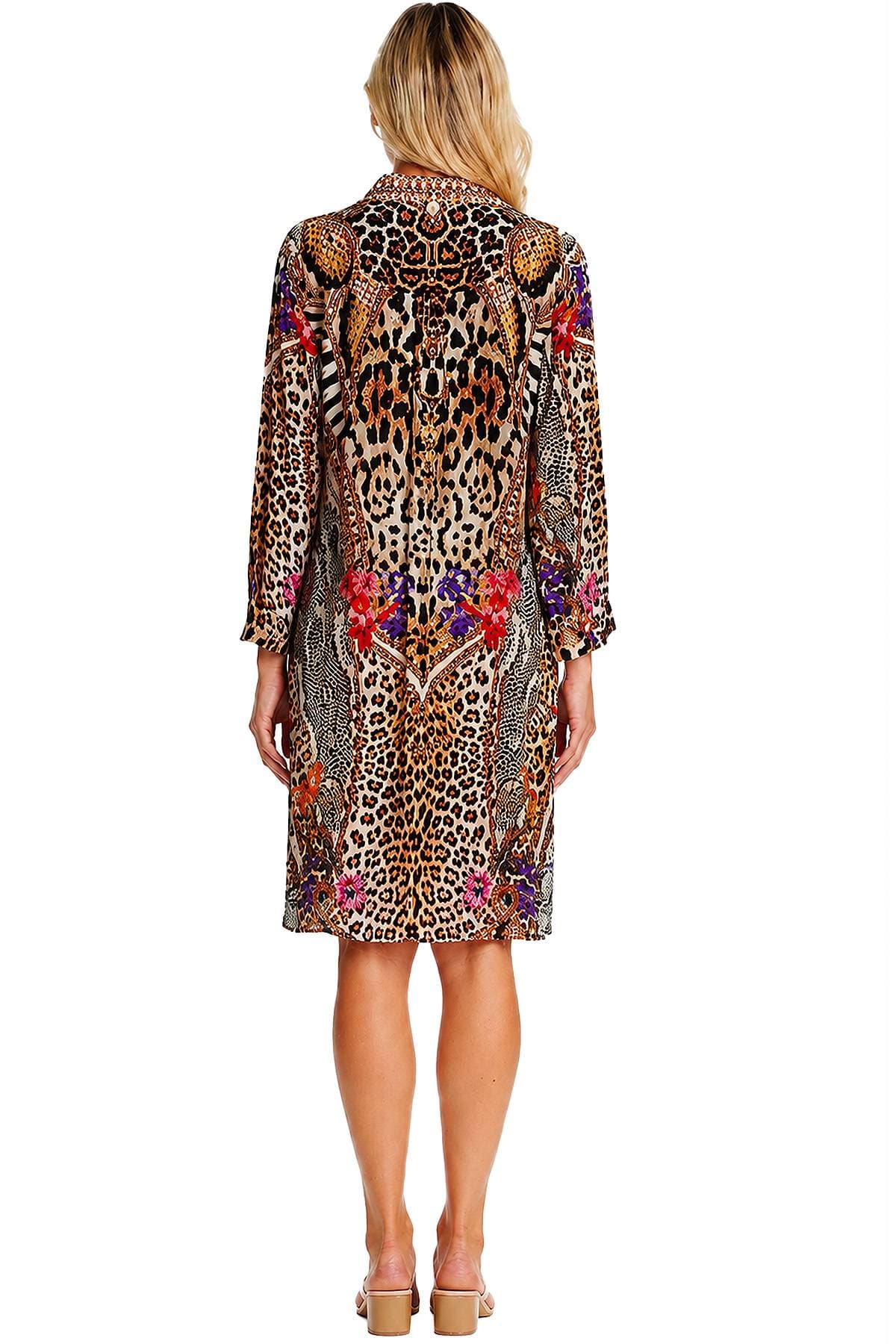 A person wearing a knee-length dress with a colorful, intricate animal print design viewed from the back.