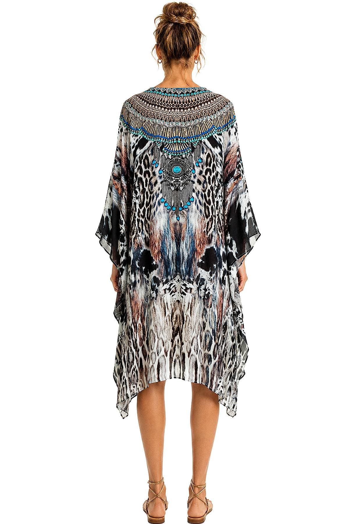 A person wearing a long, flowing dress with a colorful, intricate animal print and beaded accents on the back.