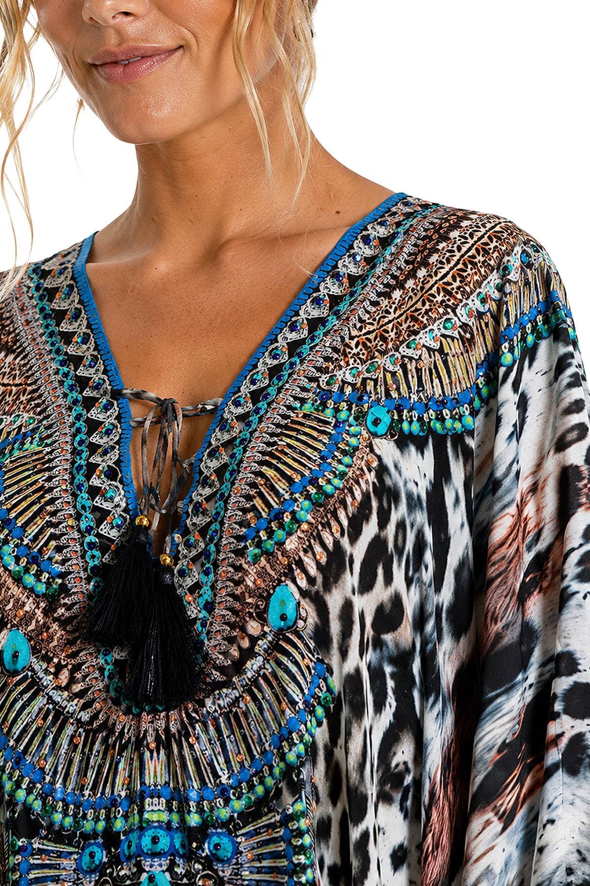A person is wearing a colorful, intricately patterned top with decorative tassels.