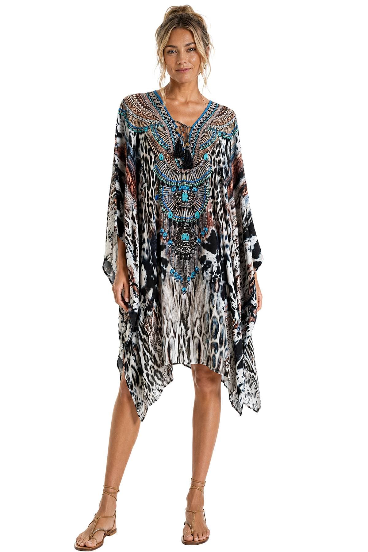 A person wearing a patterned kaftan dress with intricate designs and bright blue accents.