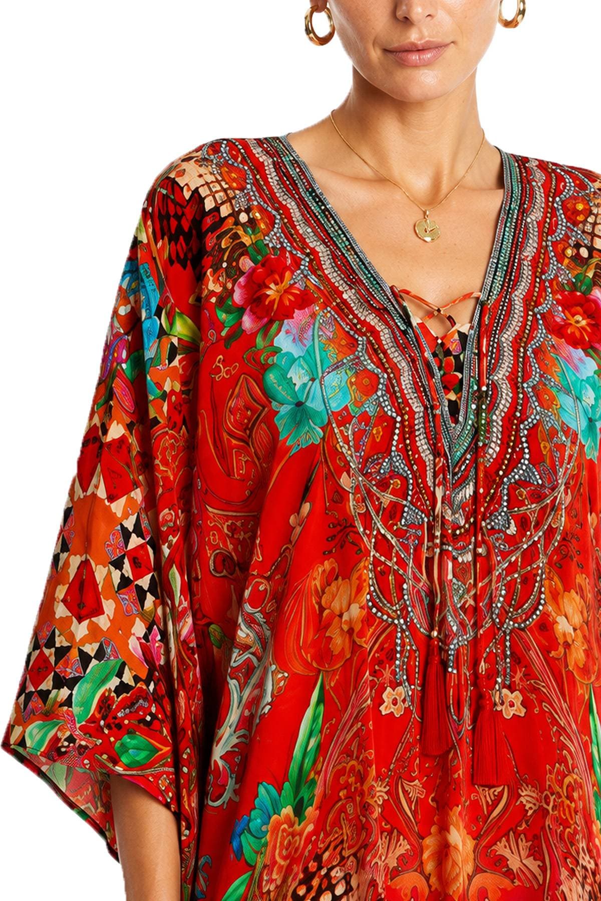 A person wearing a colorful red garment with intricate floral and geometric patterns and embroidery.