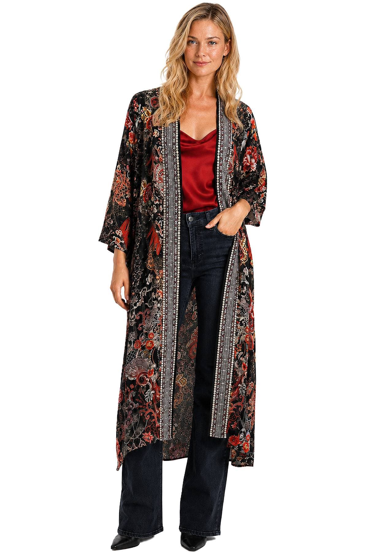 A woman wearing a long, patterned kimono over a red top and dark jeans.