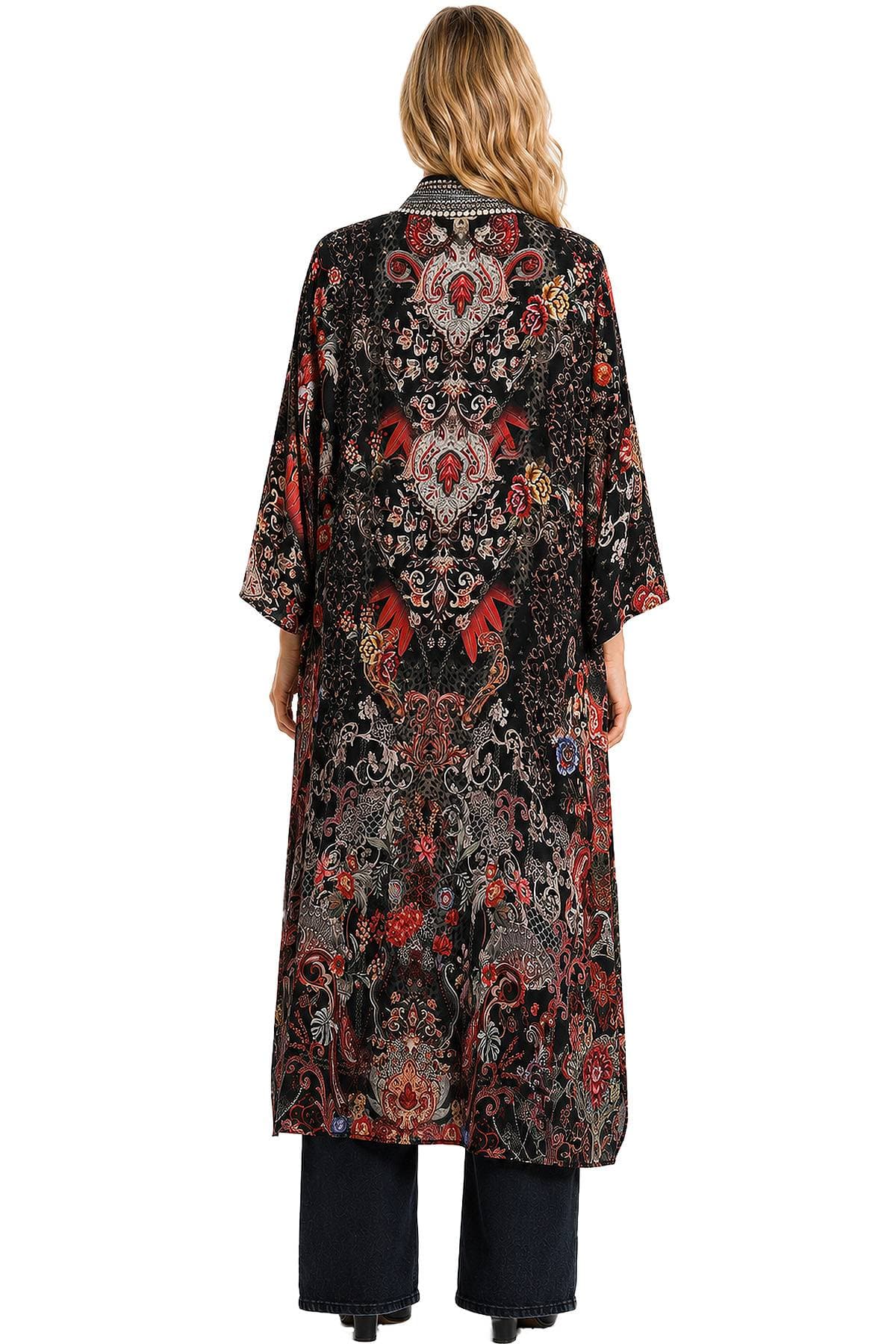 A person is wearing a long, patterned black and red kimono-style robe with floral motifs, viewed from the back.