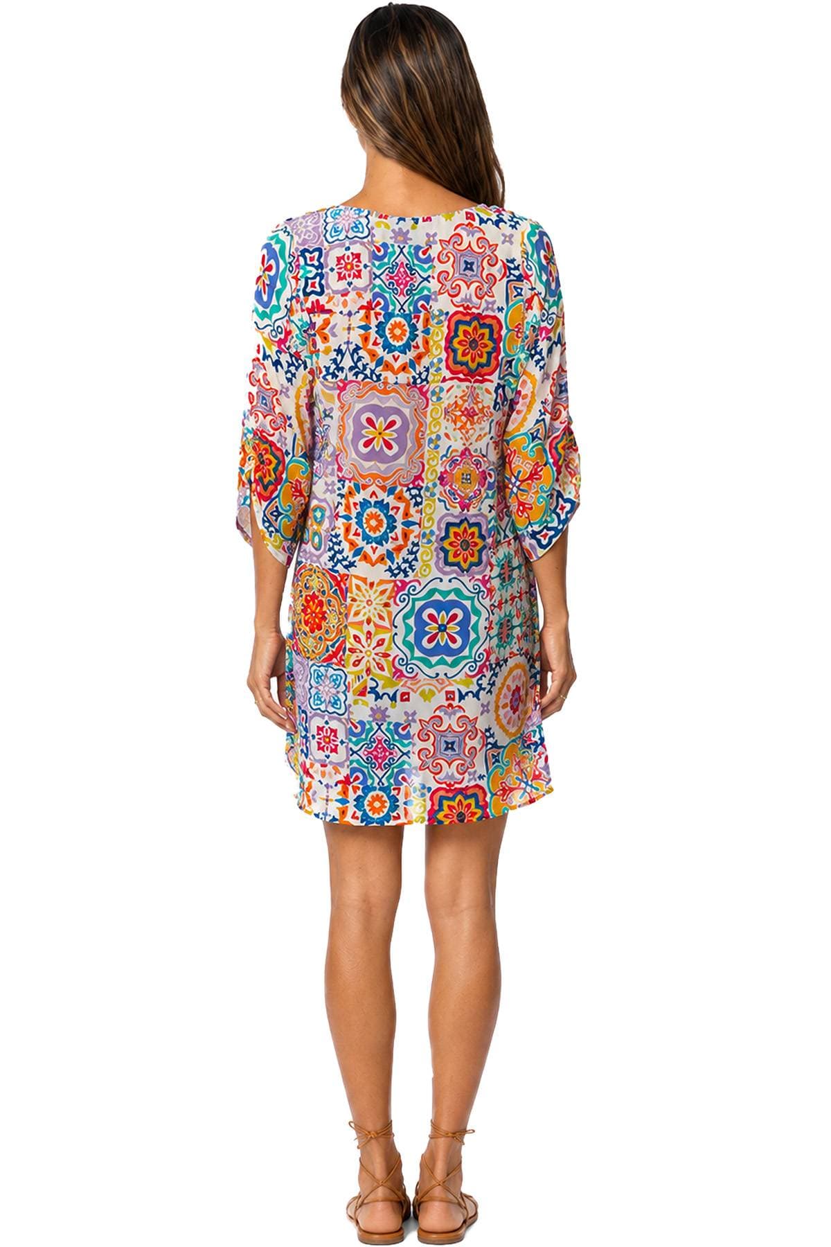 A person is wearing a colorful patchwork-patterned dress and brown sandals, facing away from the camera.