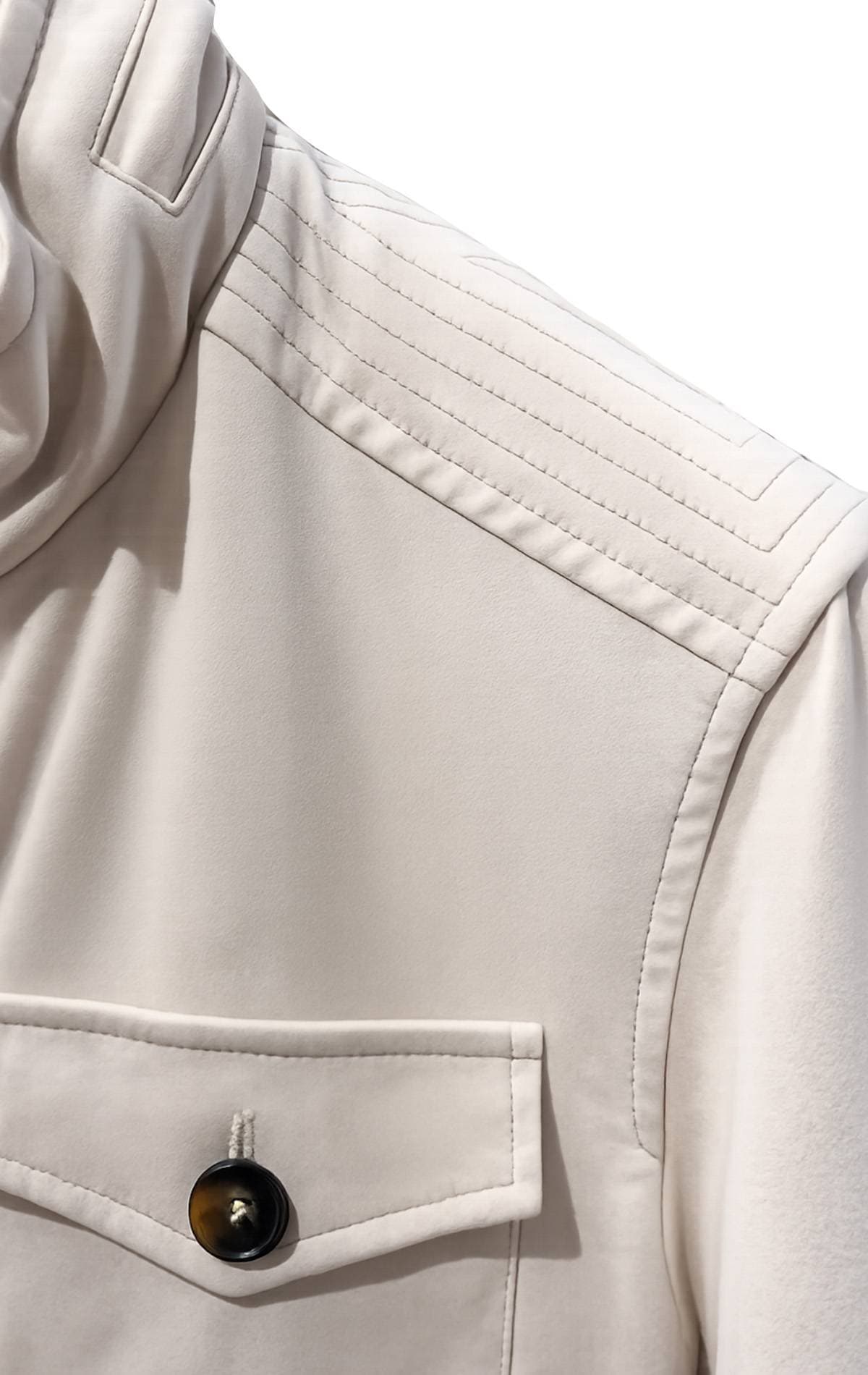 Close-up of a beige jacket with a black button and a flap pocket.