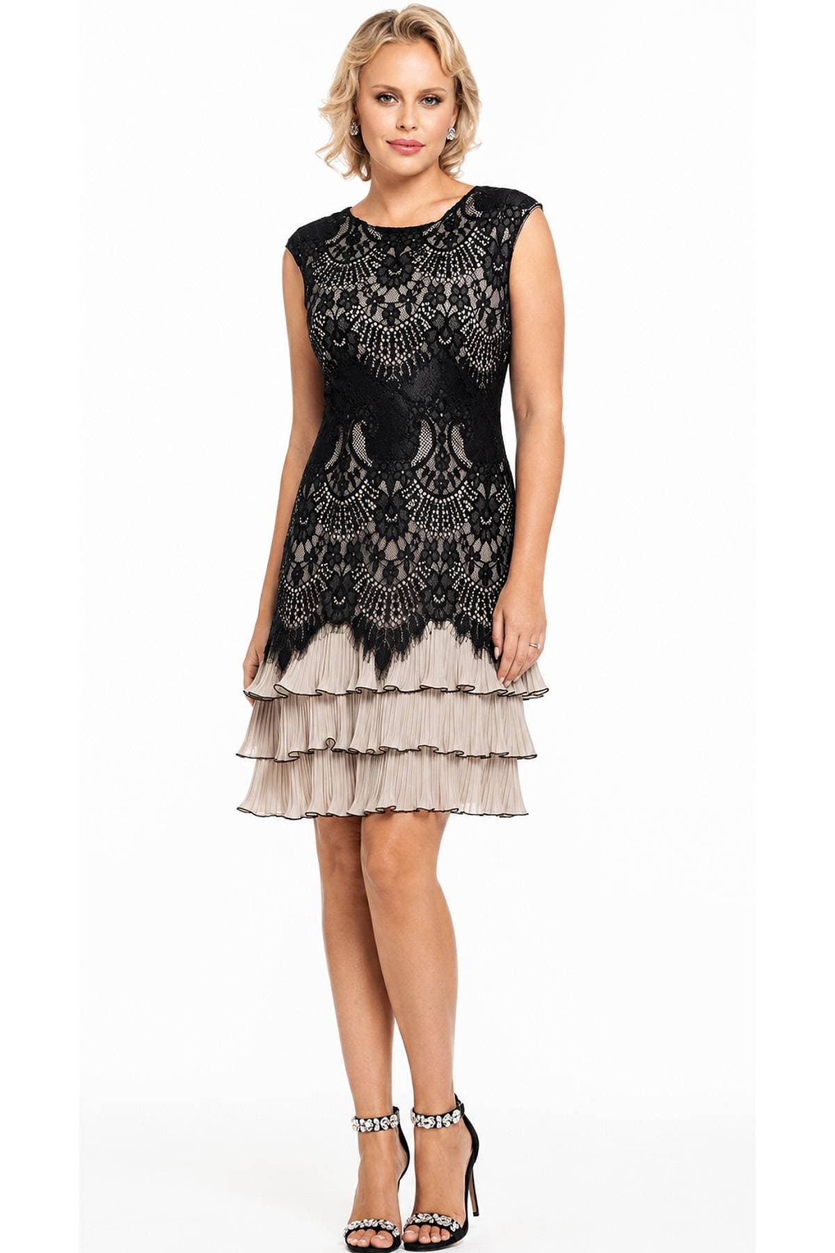 A woman is wearing a sleeveless black lace dress with a tiered beige skirt and embellished black heels.