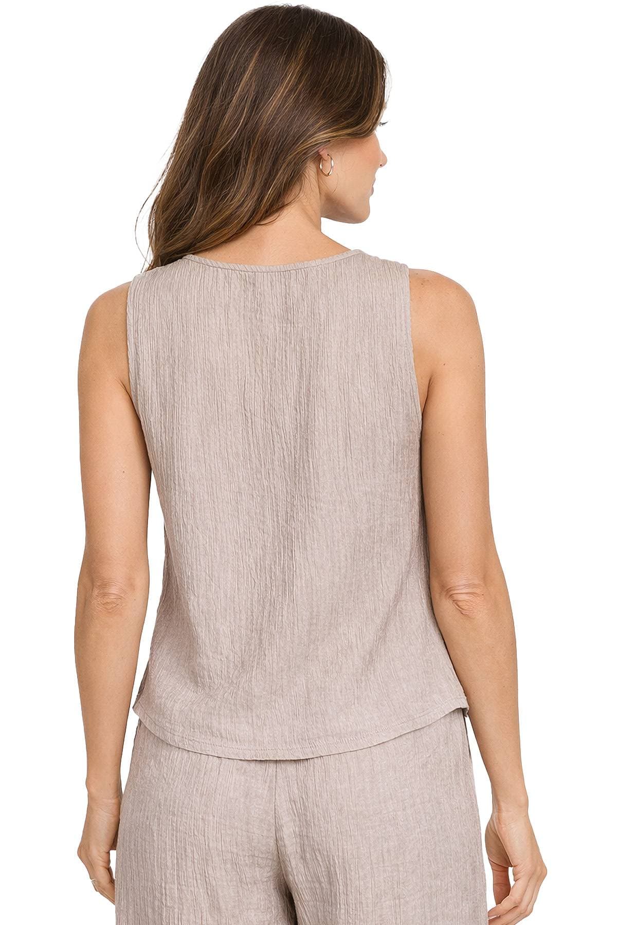 A woman is wearing a sleeveless beige top and matching pants, viewed from the back.
