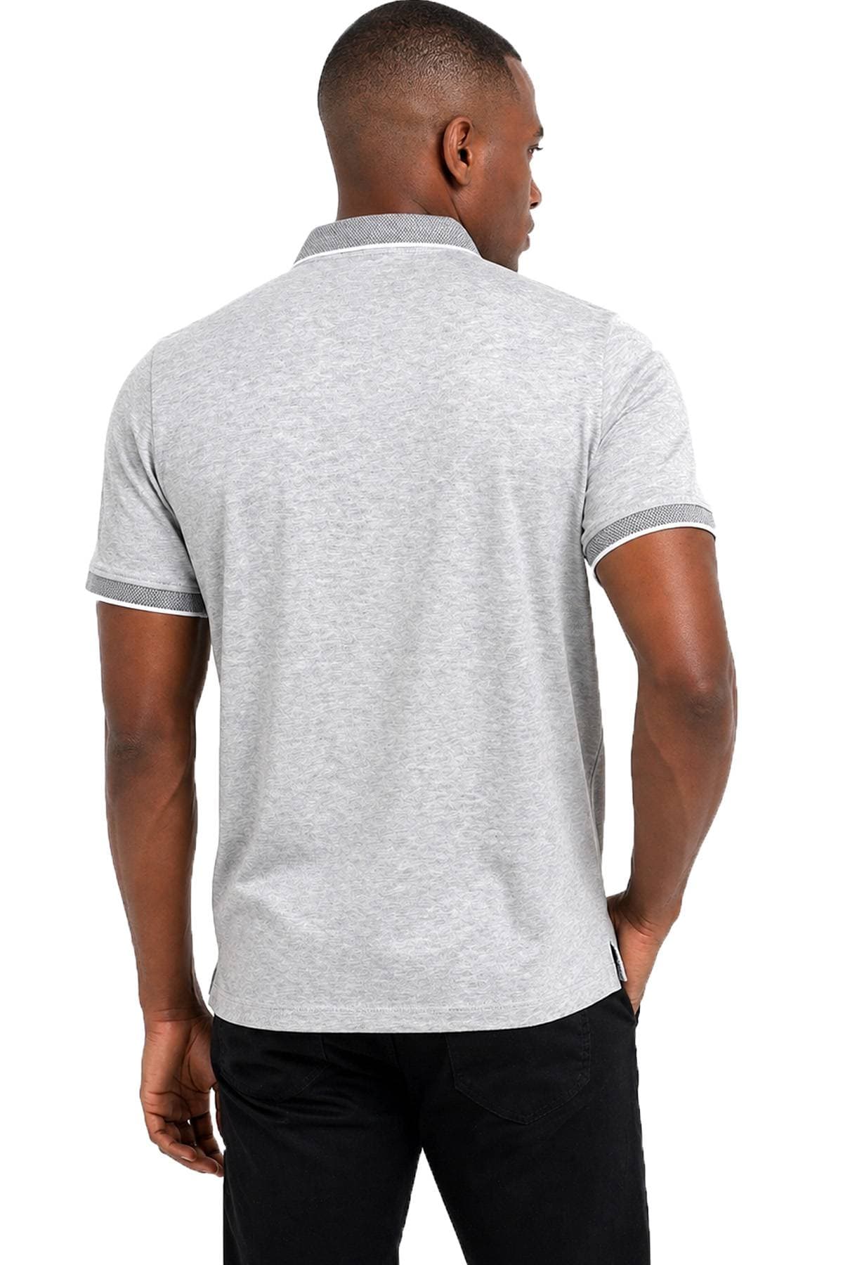 A person wearing a light gray polo shirt and black pants is facing away from the camera.