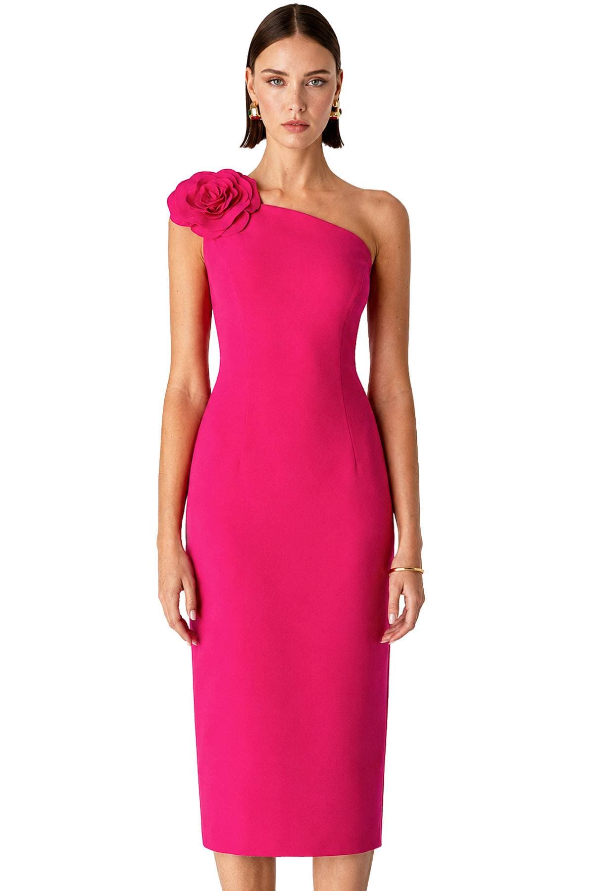 A woman is wearing a bright pink one-shoulder dress with a large floral embellishment on the shoulder.